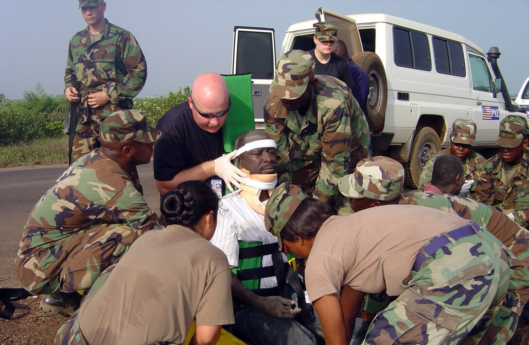Senior Master Sgt. Daryl Webb (in sunglasses) and Tech. Sgt. Elizabeth Burrell (in a black T-shirt) join members of the Armed Forces of Liberia in stabilizing a victim from an auto accident in January in Liberia. The Airmen are medics with U.S. Air Forces in Europe from Ramstein Air Base, Germany. The Armed Forces of Liberia medical technicians  had just completed two days of medical training by USAFE Airmen. (U.S. Air Force photo/Maj. Kimberly Pietszak)