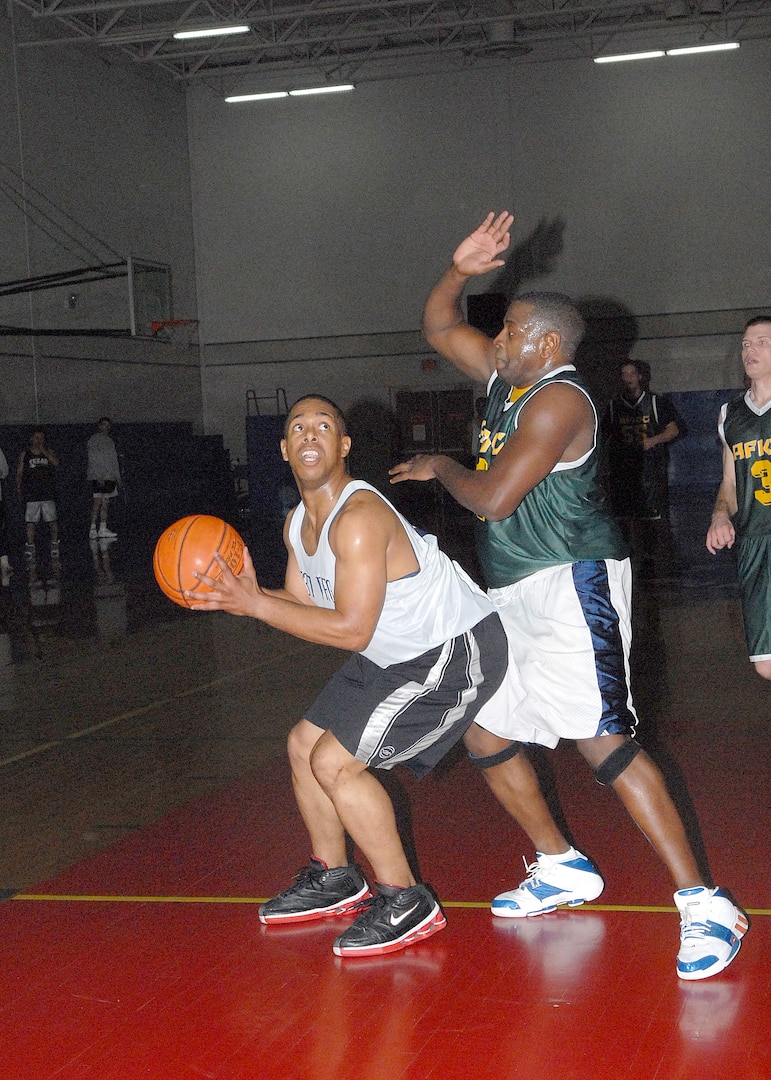 While being covered by Curt Robertson from Air Force Information Operations Center, Ryan Nichols eyes the basket for the 737th Training Group during their win over the AFIOC Feb. 8 at the Chaparral Fitness Center, Lackland AFB, Texas. (USAF photo by Robbin Cresswell)