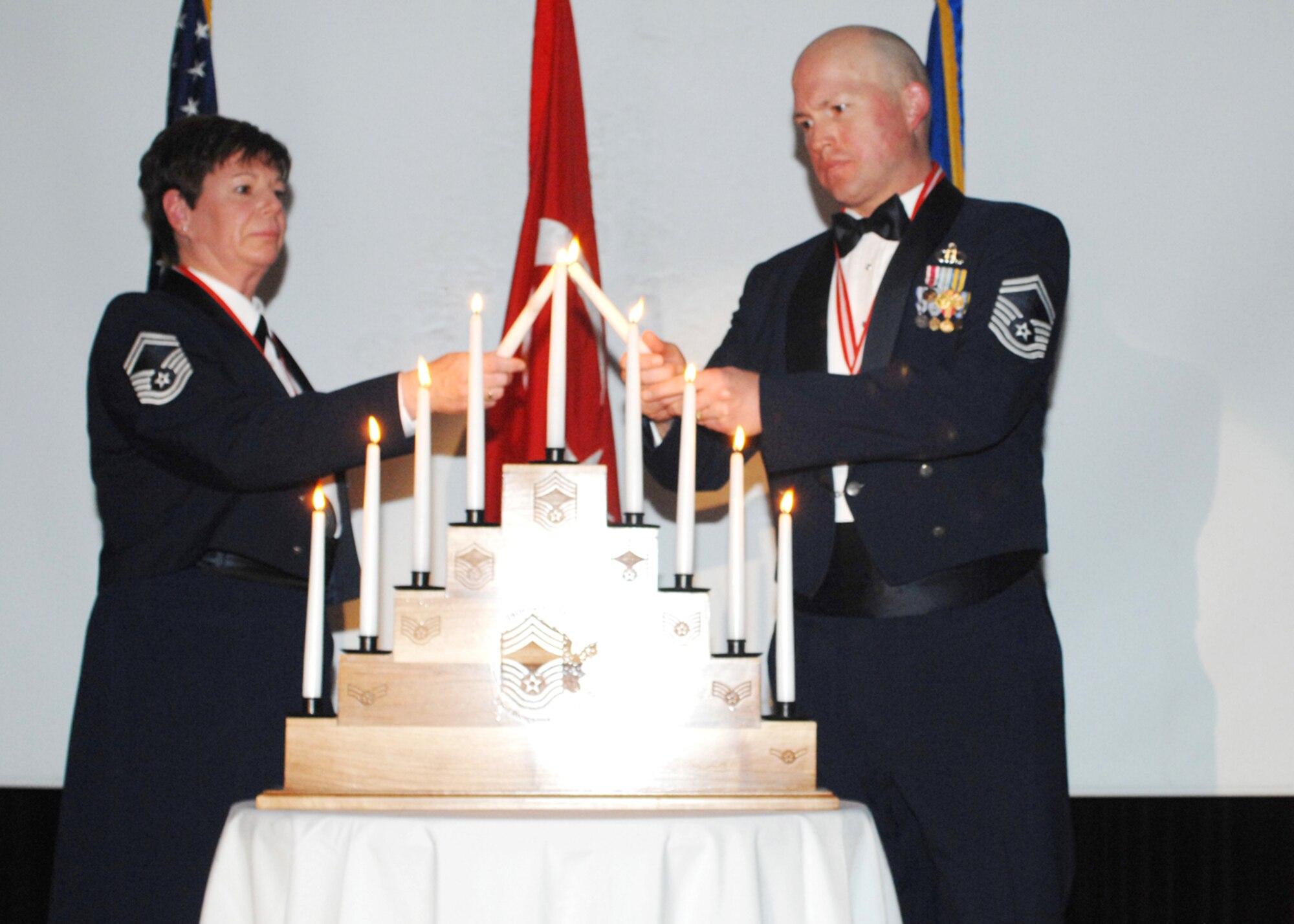 Senior Master Sgt. Denise Mikolajczyk (left) from the 39th Mission Support Squadron and Senior Master Sgt. Steven Lantz from the 39th Operations Squadron light the last progression of grades candles together during a Chief Induction Ceremony Feb. 9 at the Consolidated Club. (U. S. Air Force photo by Tech. Sgt. Shirley Henderson)