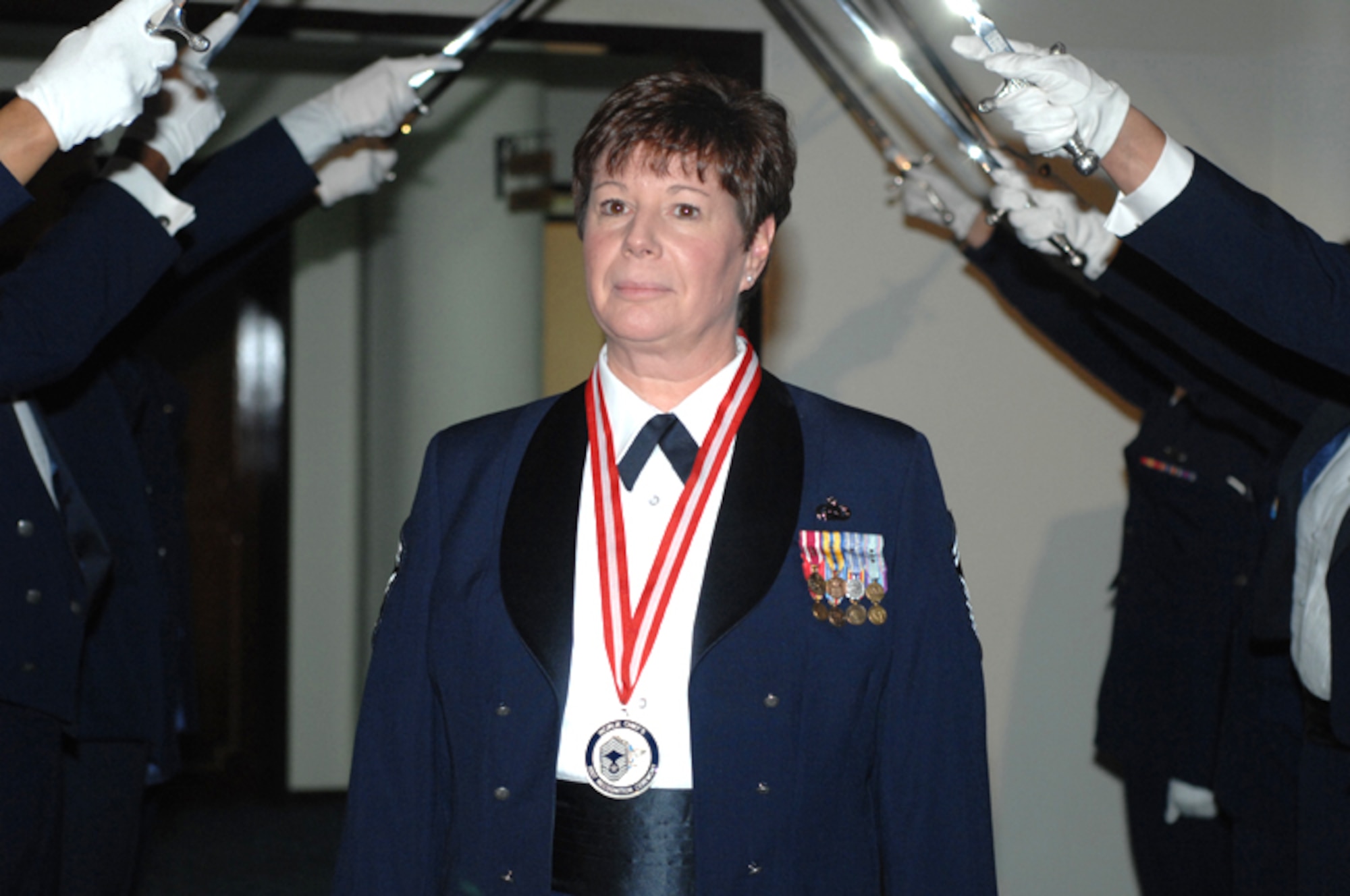 Senior Master Sgt. Denise Mikolajczyk from the 39th Mission Support Squadron passes through the Honor Guard cordon of swords during the Chief Induction Ceremony Feb. 9 at the Consolidatedd Club. (U. S. Air Force Photo by Technical Sergeant Shirley Henderson)