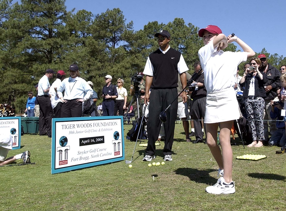 Golfer Tiger Woods watches the swing of 11yearold Emily Gaylord