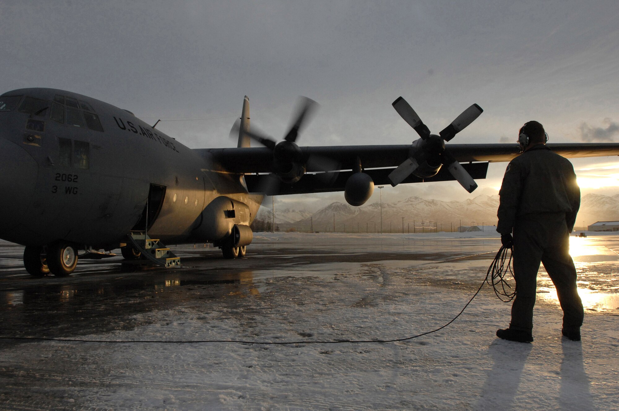 An Airman directs engine start up on a C-130 Hercules prior to an training mission Feb. 1 from Elmendorf Air Force Base, Alaska. The C-130 belongs to the 517th Airlift Squadron. The 517th AS will replace its fleet of C-130s with the C-17 Globemaster III in 2007. (U.S. Air Force photo/Tech. Sgt. Keith Brown) 

