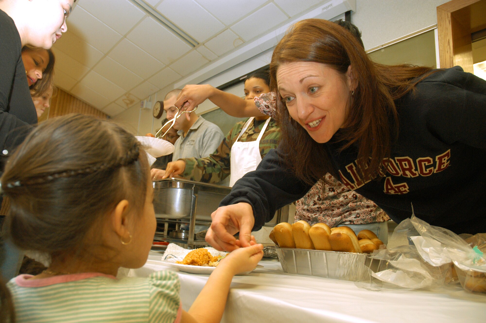 Tech. Sgt. Melissa Hargis examines a piece of valentine candy that Mikayla, age 3, brought to show her. Mikayla and her mother, Kamille Benitez, attended the deployed spouses' dinner at the Peterson Air Force Base, Colo., earlier this month as part of the base's efforts to support spouses of deployed Airmen. Mikayla's father, Staff Sgt. Michael Benitez, is deployed to Afghanistan from the 50th Security Forces Squadron at Schriever Air Force Base, Colo. Sergeant Hargis is assigned to the 21st Medical Support Squadron here. (U.S. Air Force photo/Staff Sgt. Don Branum)