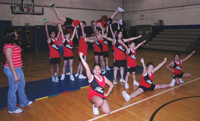 OSAN AIR BASE, Republic of Korea --  Tech. Sgt. Kaleah Hodges (left), cheerleading coach for the Youth Center Sports Program, instructs the girls in how to do the "pyramid." The cheerleading squad is for girls from 9-12 years old. (U.S. Air Force photo by Staff Sgt. Benjamin Rojek)
