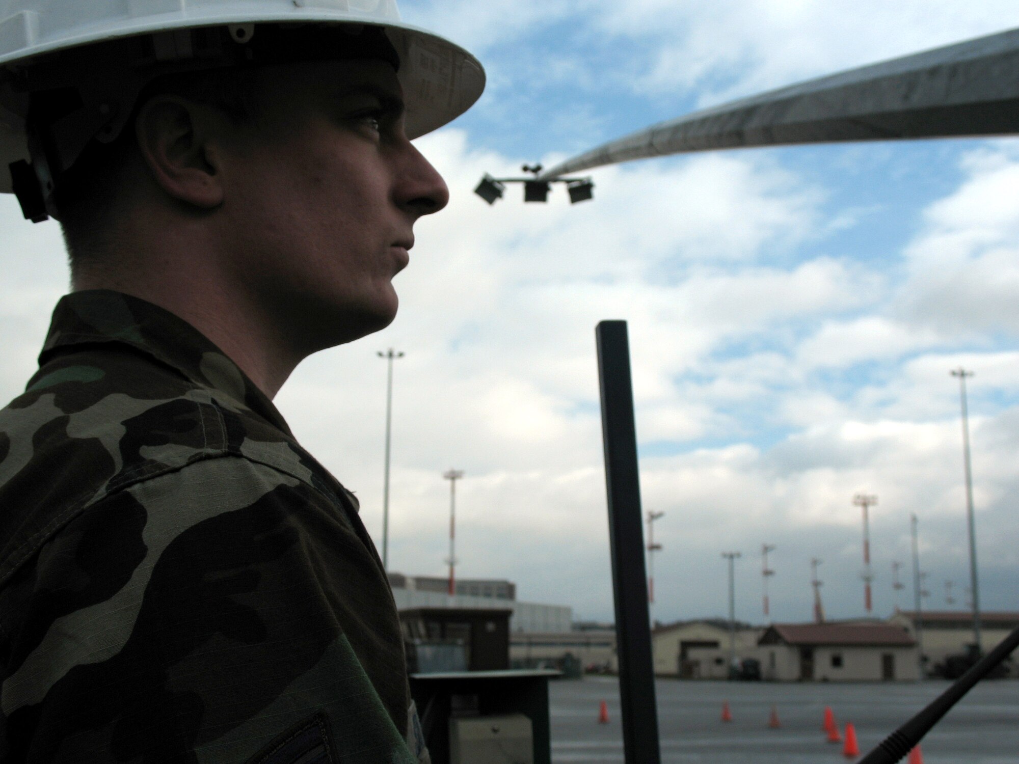 Staff Sgt. Brian Sawyer, an electrical systems craftsman at Ramstein Air Base, Germany, observes as an 80-foot light pole on the flightline is lowered Feb. 13 to permit his civil engineer team to check the bulbs that have ceased working.  (U.S. Air Force photo/Airman 1st Class Mara Title)