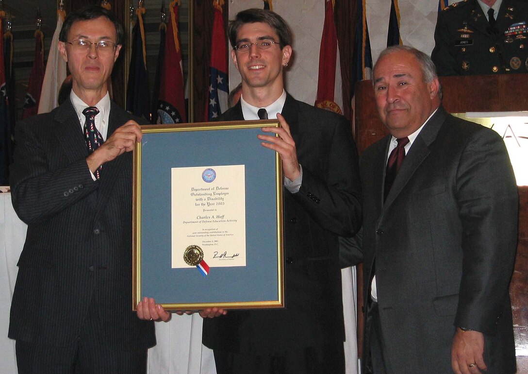 Charles A. Hoff, an audiovisual production  specialist with the Department of Defense Education  Activity, Arlington, Va., accepts the secretary of  defense certificate for outstanding employees with  disabilities from Under Secretary of Defense for  Personnel and Readiness David S.C. Chu. Hoff was born  with nystagmus, a neurological disorder that creates  rapid, involuntary eye movements.  He is legally blind  and colorblind and often relies on a combination of  software, color measurement devices and colleagues to  ensure proper color selection in his designs. The 23rd  Annual DoD Disability Awards Ceremony was held Dec. 9 at  the Hyatt Regency Hotel in Bethesda, Md. Photo by K.L.  Vantran.