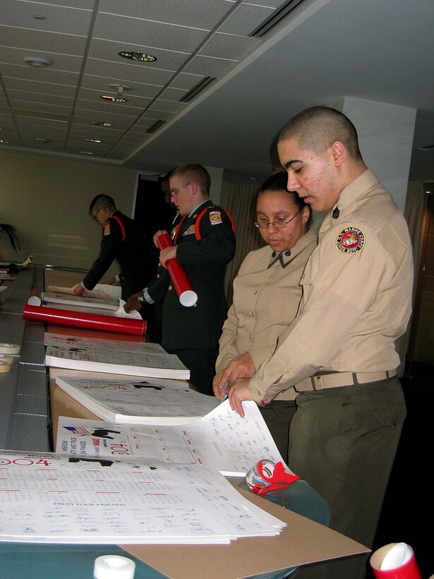 Junior ROTC cadets  Marine Gunnery Sgt.  Eduardo Negron, Marine Sgt. Latasha McMillan, Army Staff  Sgt. James Byrne, Army Staff Sgt. Aaron Hope and Army  Command Sgt. Maj. Andrew Pham  pack 2004 calendars. The  calendars, which feature Parade magazine's cartoon dog  Howard Huge, will be mailed to deployed troops overseas.  Task Force Calendar 04 is sponsored by the White House  Commission on the National Moment of Remembrance. Photo by  K.L. Vantran.