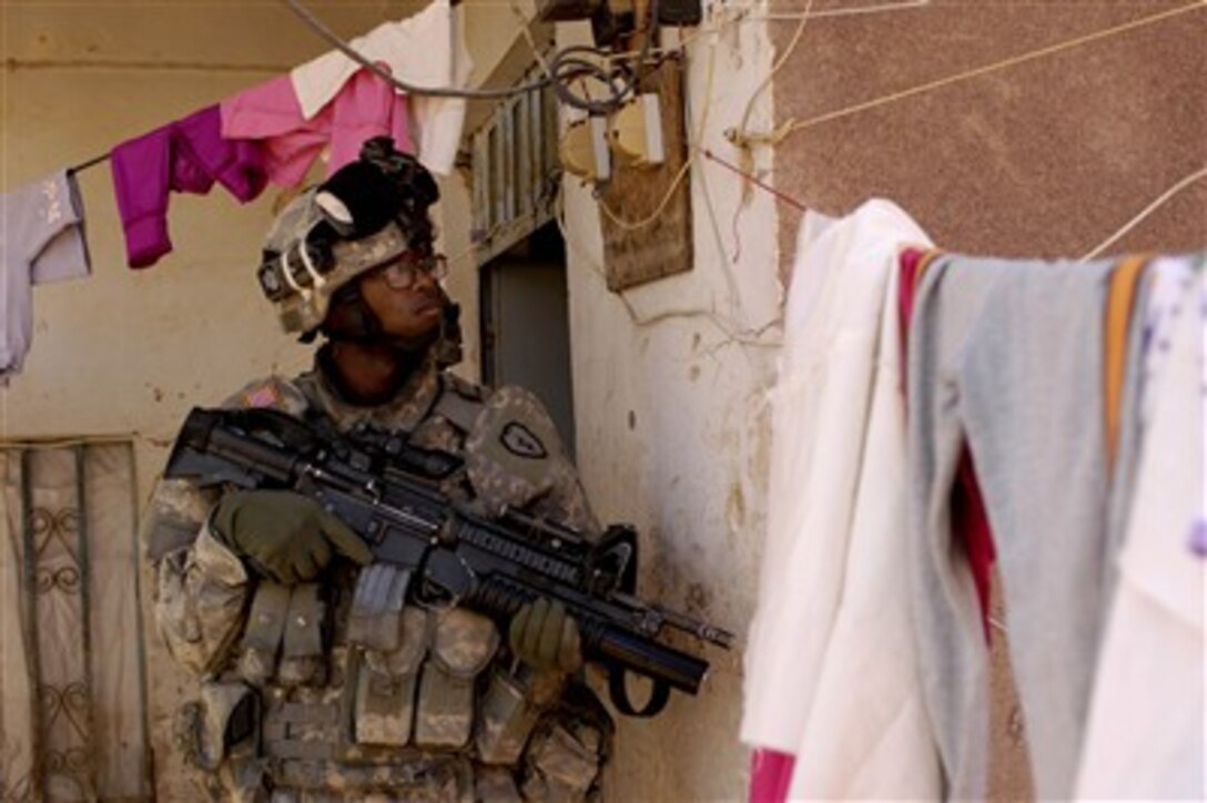 U.S. Army Pfc. Marcus Handcock looks between the laundry lines as he provides security for his fellow soldiers who are conducting a house search with Iraq army soldiers during a patrol in Riyahd, Iraq, on Feb. 8, 2007.  Handcock is assigned to Alfa Company, 2nd Battalion, 27th Infantry Regiment, 3rd Brigade Combat Team, 25th Infantry Division.  