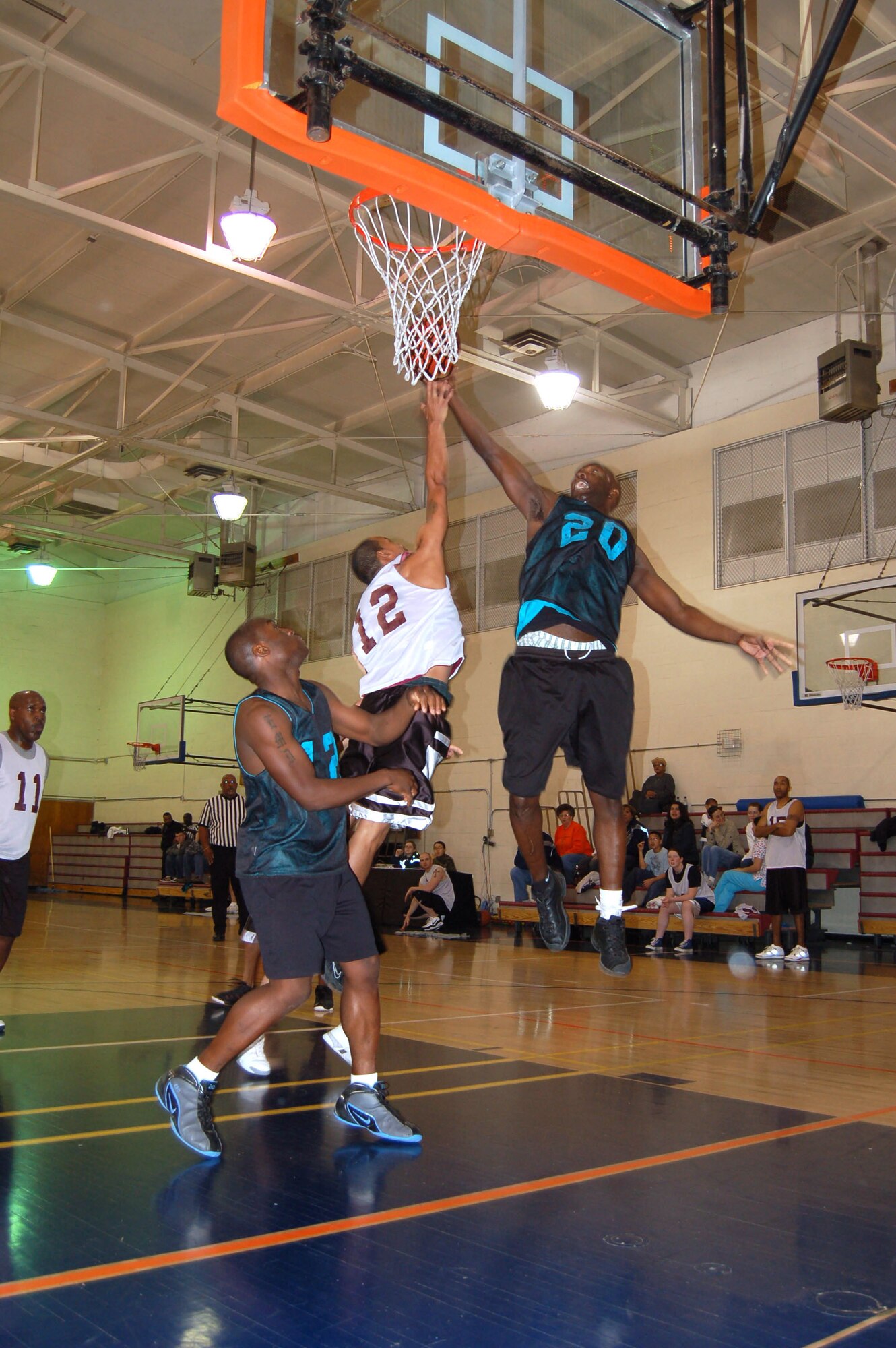 Buster Evans (No. 20), Marine Aircraft Group Detachment Bravo, performs a lay-up as Thomas Jones (No. 12), 95th Medical Group, blocks during the championship of the basketball intramural Feb. 9, 2007. (Photo by Airman 1st Class Julius Delos Reyes)