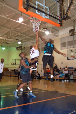 Buster Evans (No. 20), Marine Aircraft Group Detachment Bravo, performs a lay-up as Thomas Jones (No. 12), 95th Medical Group, blocks during the championship of the basketball intramural Feb. 9, 2007. (Photo by Airman 1st Class Julius Delos Reyes)