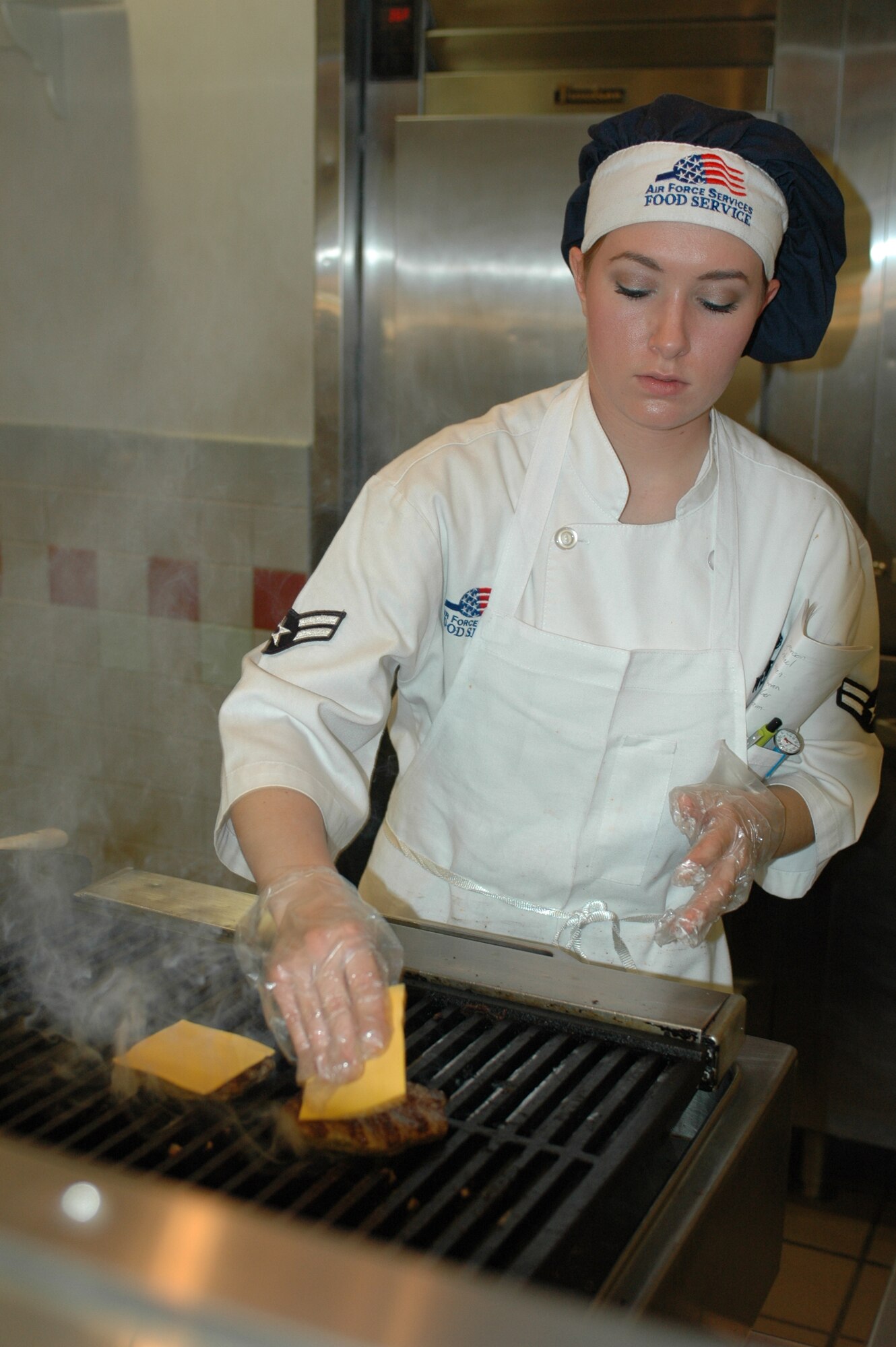 Airman 1st Class Sara Weber adds cheese to a customer’s hamburger during the dinner shift. The 60th Services Squadron’s Food Service Flight is preparing for the 2007 Air Force Hennessy Award competition. The award is presented to the Air Force base with the best food service program, evaluates all aspects of a facility’s program including kitchen operations, serving and dining operations, training and readiness, sanitation and repair, and management. (U.S. Air Force photo by Staff Sgt. Candy Knight)