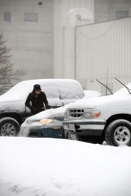 An Electronic Systems Center employee braves the harsh conditions to clean off her vehicle on Wednesday. Precipitation blanketed the ground making driving difficult. (US Air Force Photo by 1st Lt. Geoff Buteau)