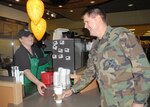 A barista serves Col. Eric Wilbur, the 37th Training Wing vice commander at Lackland Air Force Base, Texas, the first cup of joe Feb. 14 during a ribbon cutting ceremony for the newest coffee shop on base. Located in the Basic Military Training Food Mall, Bldg. 7025, Starbucks will be open Monday-Friday from 6 a.m. to 8 p.m., and Saturday and Sunday from 7 a.m. to 8 p.m. Patrons who bring their own coffee mug will receive 10 cents off their purchase. (USAF photo by Robbin Cresswell)