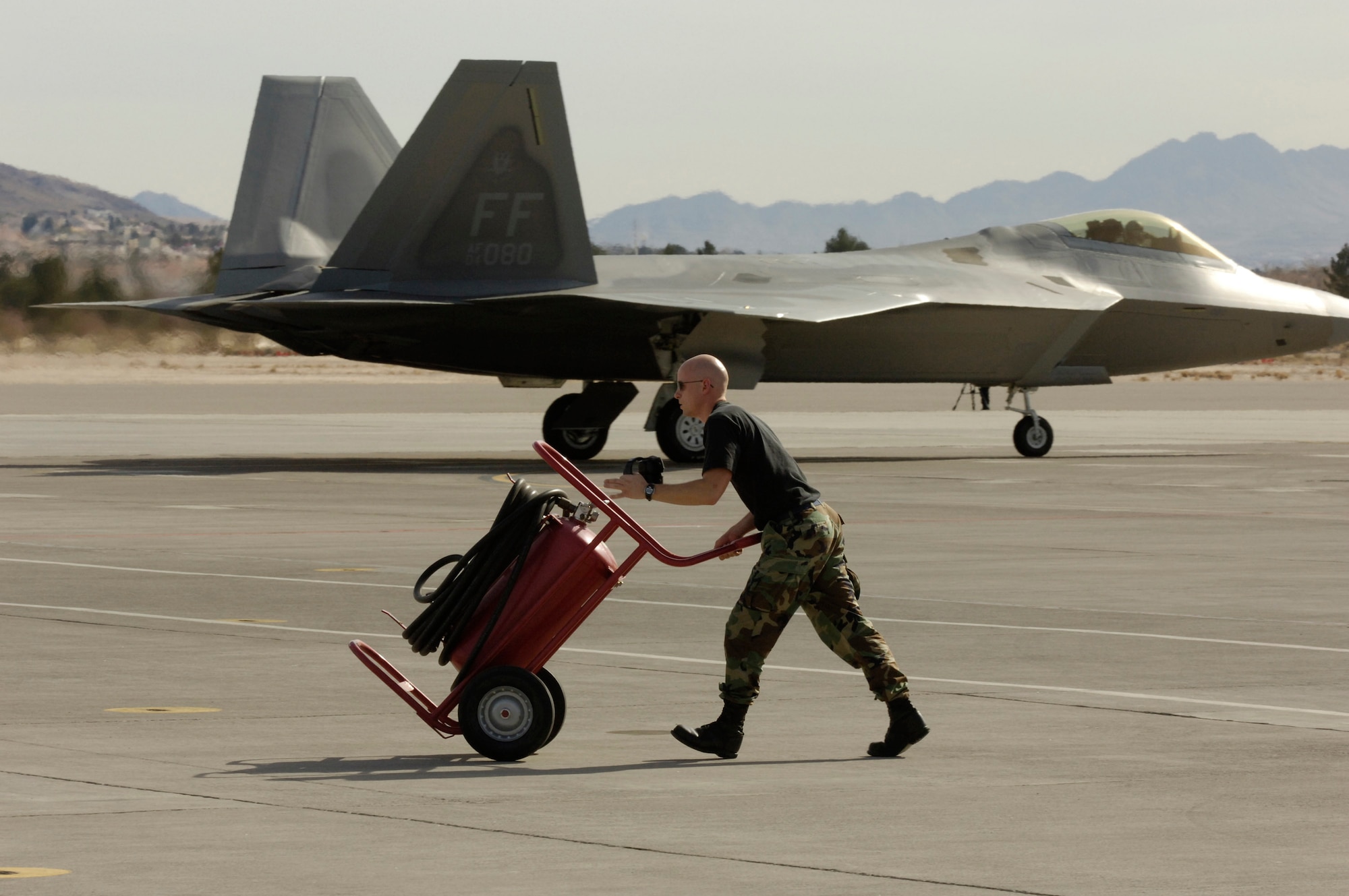 Tech. Sgt. Kasper Kolbe pushes a fire hose cart during Red Flag Feb. 6 at Nellis Air Force Base, Nev. Red Flag sharpens aircrews' warfighting skills in realistic combat situations. The aircraft are flying missions day and night at the nearby Nevada Test and Training Range where they simulate an air war. Sergeant Kolbe is an avionics specialist at the 94th Fighter Squadron at Langley AFB, Va. (U.S. Air Force photo/Master Sgt. Kevin J. Gruenwald)