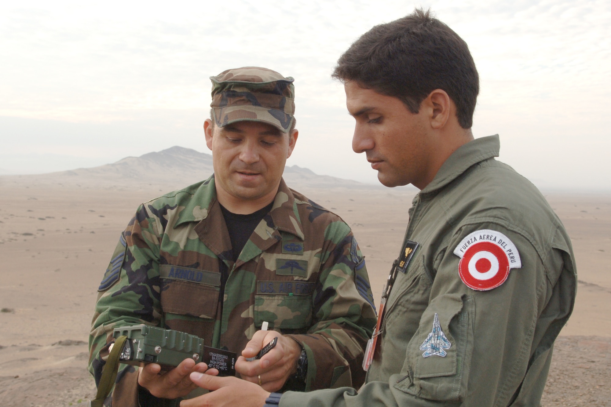 Master Sgt. Jesse Arnold goes over operations of a transmitter with a Peruvian pilot during a joint combat search and rescue exercise Feb. 14 near Chiclayo, Peru. The exercise was part of Falcon and Condor 2007, a joint exercise between the U.S. and Peruvian Air Forces. Sergeant Arnold is an Air Force survival, evasion, resistance and escape specialist. (U.S. Air Force photo/Tech. Sgt. Kerry Jackson)