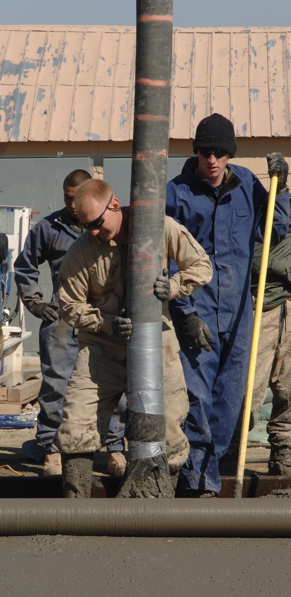 Senior Airman Trafton Wieland (left) and Airman First Class James McFarland (right), both of the 455th Expeditionary Civil Engineer Squadron, place concrete for a new logistics facility at Bagram Airfield, Afghanistan, Feb. 14. (U.S. Air Force photo/Capt. Travis Tougaw)