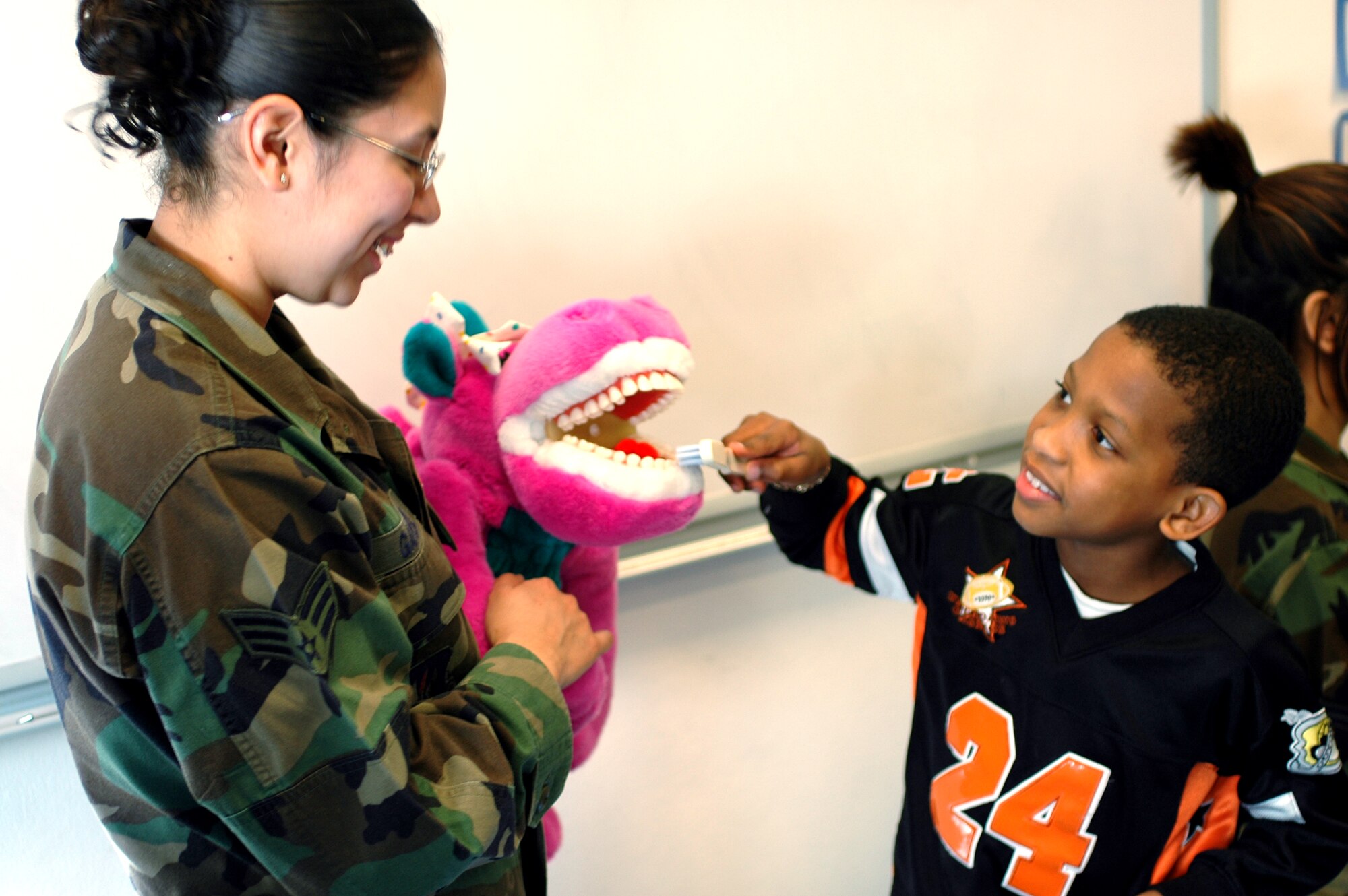 Senior Airman Sarai Gapetz, 31st Dental Squadron dental assistant, shows  second grader Zyrie Palmer the proper technique for brushing teeth during a visit to Aviano’s Elementary School Wednesday.  The technicians visited the second grade class for National Children’s Dental Health Month. (Photo by Tech. Sgt. Jerome Baysmore)