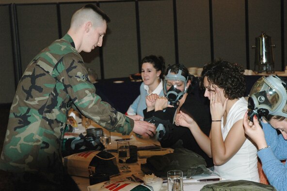 OSAN AIR BASE, Republic of Korea --  Airman Adam Smith, 51st Civil Engineer Squadron readiness apprentice, shows spouses how to wear the gas masks they were issued during the Airmen and Family Readiness Spouse Orientation Feb. 9. During the orientation, spouses meet with base leadership, learn about noncombatant evacuation operations, Korean culture and various base services available to them. The next orientation is March 2. To sign up, call 784-5440. (U.S. Air Force Senior Airman Brok McCarthy)