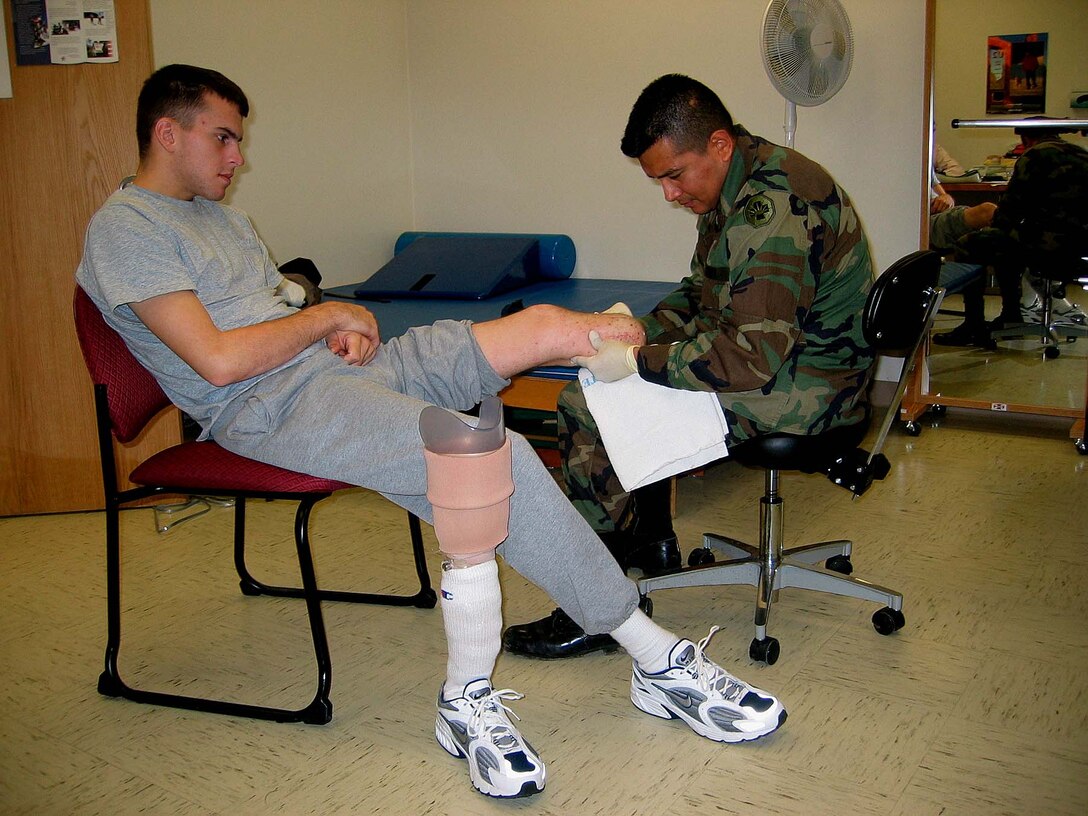 Army Spc. Harvey Naranjo, an occupational  therapy assistant at Walter Reed Army Medical Center in  Washington, massages Spc. Brian Wilhelm's leg, as part of  Wilhelm's therapy. Wilhelm was wounded in battle in Iraq on  Oct. 7. He has been at Walter Reed since Oct. 11. Photo by  Jamie Reese.
