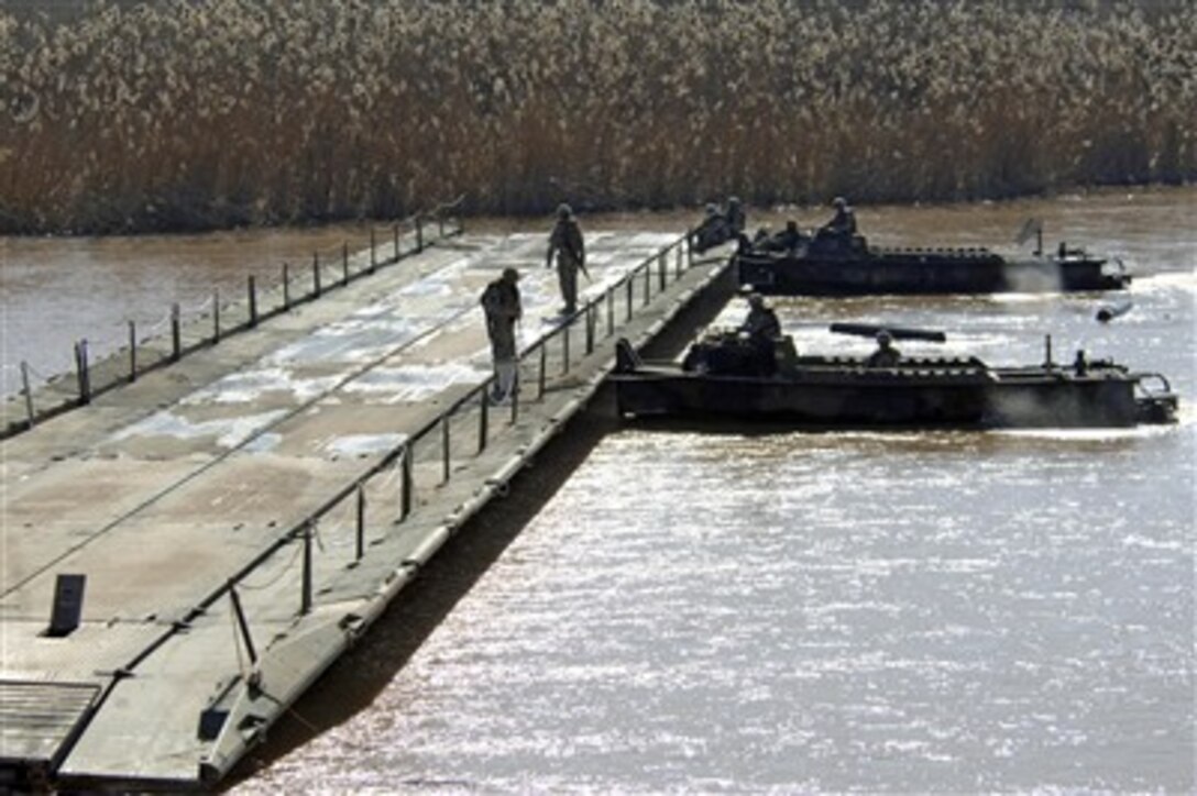 A team of build boats from the 502nd Multi-role Bridge Company, 1st Armor Division, push a newly assembled assault float bridge section upstream outside Camp Taji, Iraq, on Feb. 11, 2007.  