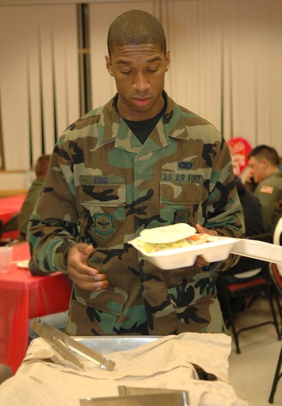 Airman 1st Class Dana King, 92nd Aircraft Maintenance Squadron information manager, loads up a box of food to go. Once a month, the chapel and a different organization on base host a dinner, which is open to single servicemembers. This month’s dinner was hosted by the 92nd Operations Support Squadron. (U.S. Air Force photo/Staff Sgt. Larry Carpenter)