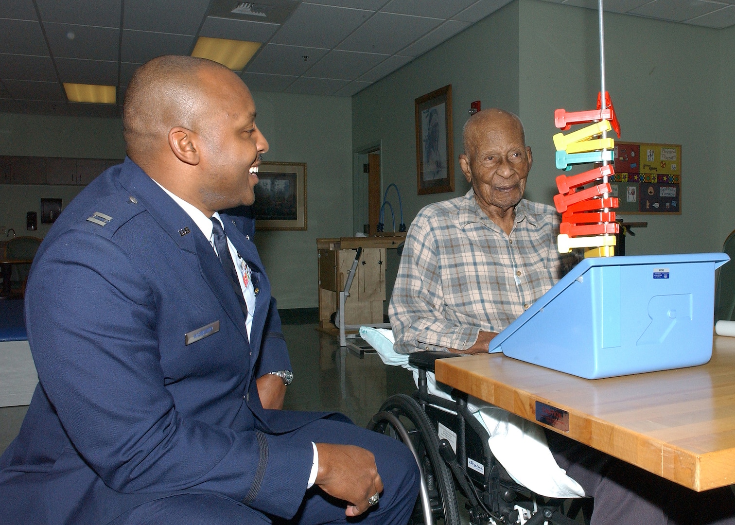 Capt. Charles Hasberry Jr. talks with 100-years-and-5-months-old Johnny Jones, a resident at the Frank M. Tejeda Texas State Veterans' Home in Floresville. Captain Hasberry is assigned to the 67th Network Warfare Wing at Lackland Air Force Base, Texas. Approximately 80 members of Team Lackland visited the home on Valentine's Day. While there, they delivered handmade Valentine's Day cards from students in two classes at Lackland Elementary School. (USAF photo by Alan Boedeker)                               