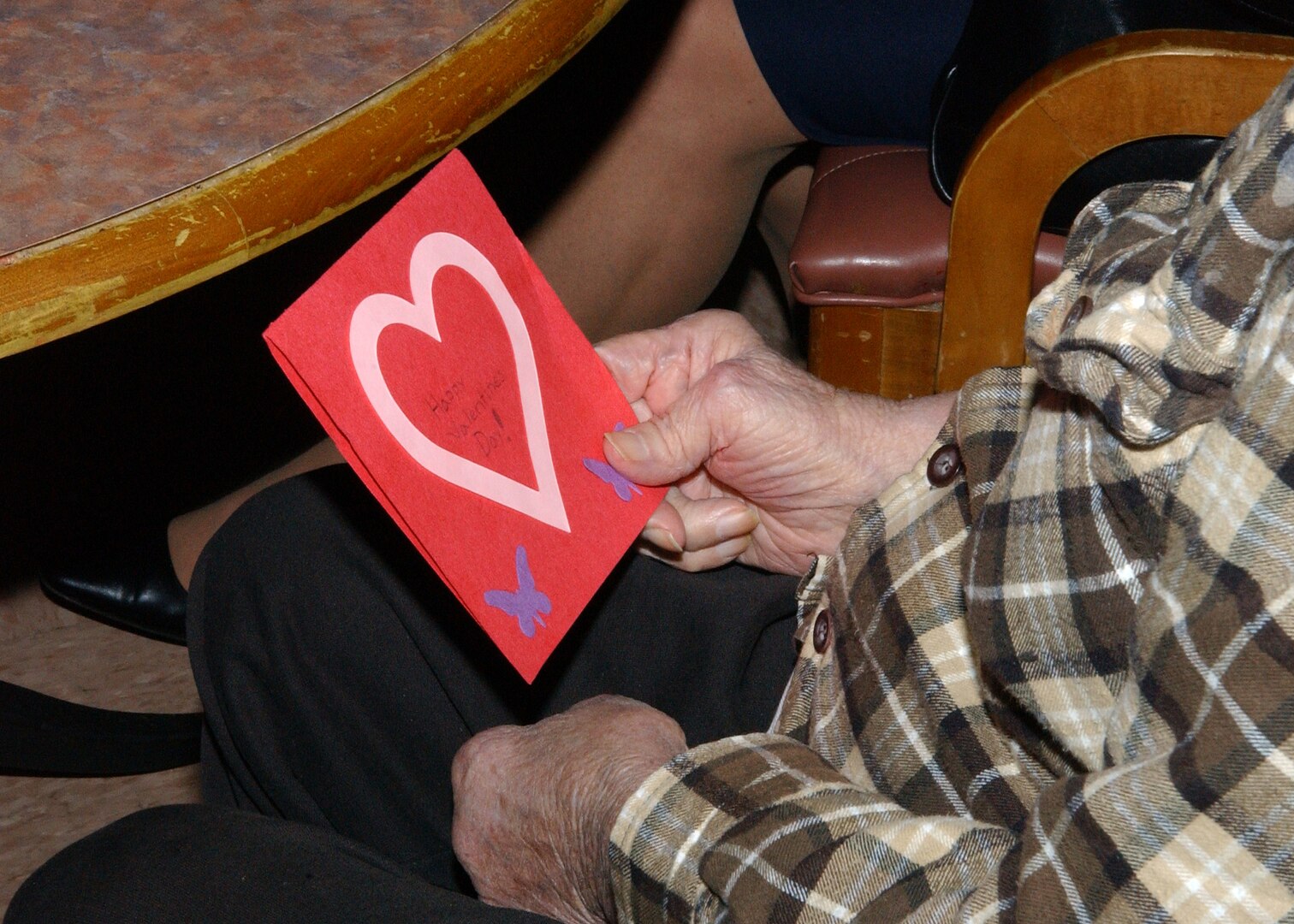 A resident of the Frank M. Tejeda Texas State Veterans' Home in Floresville grasps a handmade Valentine's Day card made by some students at the Lackland Elementary School. The cards were delivered and distributed by military and civilian Airmen from Lackland Air Force Base, Texas, on Valentine's Day. (USAF photo by  Alan Boedeker)                               