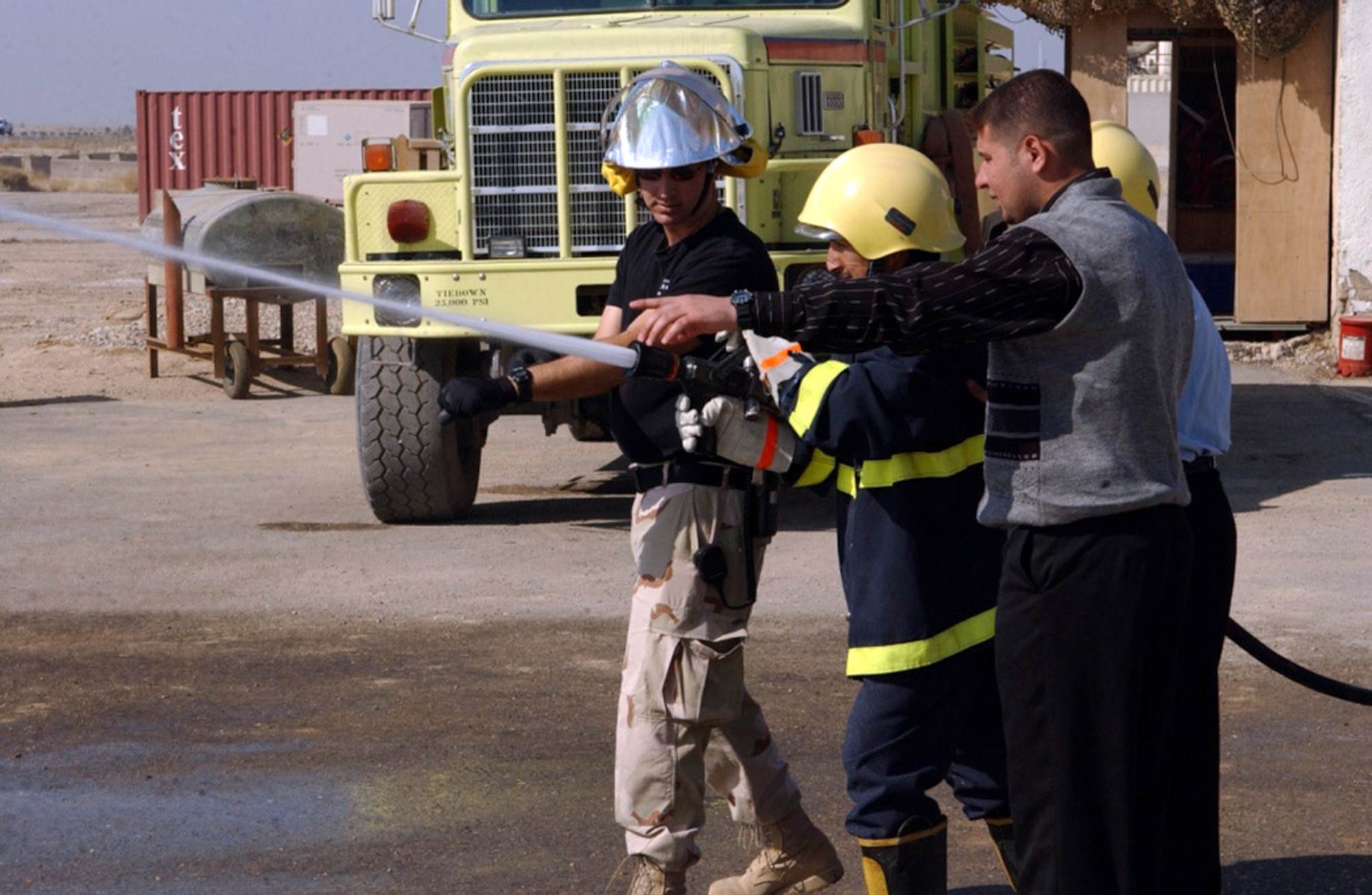 Master Sgt. Christian Anderson shows an Iraqi firefighter how to adjust the flow of water using Air Force equipment Feb. 6 at Ali Base, Iraq. Thirteen local Iraqi firefighters have been trained by members of the 407th Expeditionary Civil Engineer Squadron. Sergeant Anderson was the fire department training officer during Air Expeditionary Force 3 and 4. (U.S. Air Force photo) 
