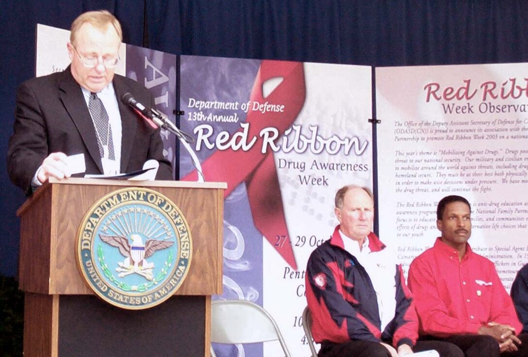 Thomas W. O'Connell, assistant secretary of defense for special  operations and low-intensity conflict, left, addresses a Pentagon audience Oct.  28 during a Red Ribbon Week ceremony. To O'Connell's right are Ron Steger,  founder of Race Against Drugs, and Bill Lester, a NASCAR truck racer. Photo by  Gerry J. Gilmore