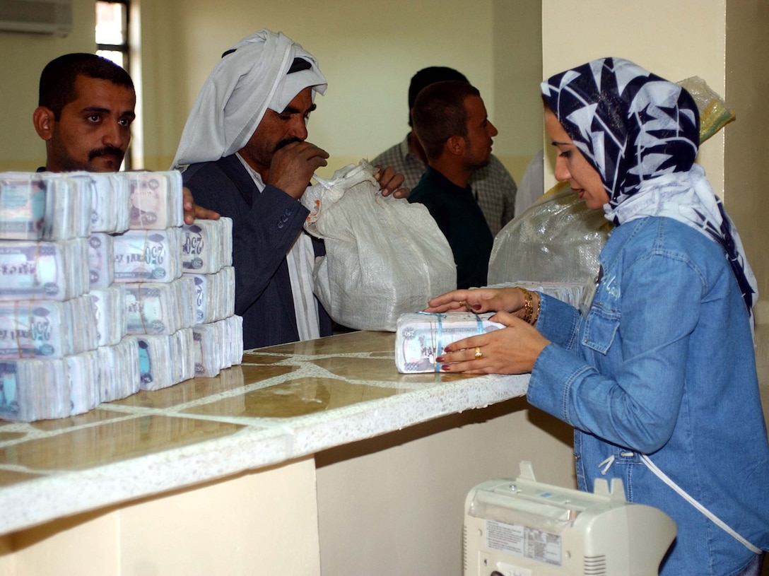 A bank worker exchanges old currency for new Iraqi dinars at  the Rasheed Bank in Mosul, Iraq, during the first day of the currency exchange,  Oct. 15. Photo by Spc. Patricia Lage, USA