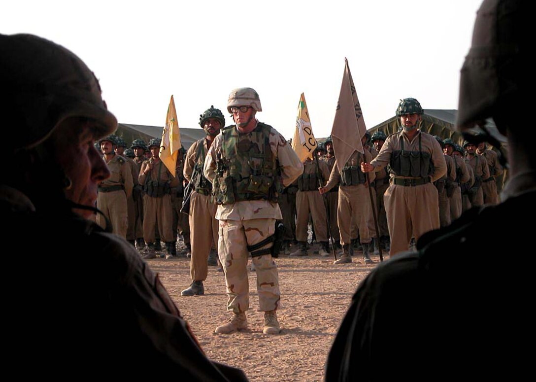 Warrant Officer Denis Pelts, officer in charge of  Iraqi Civil Defense Corps training, stands in front of a company  of ICDC soldiers as the 101st Airborne Division commander, Maj.  Gen. David H. Petreaus, looks on. The ICDC soldiers took charge  of security for Objective Jaguar from soldiers from 2nd  Battalion, 320th Field Artillery of the 101st Airborne Division.  Photo by Army Master Sgt. Kelly Tyler.