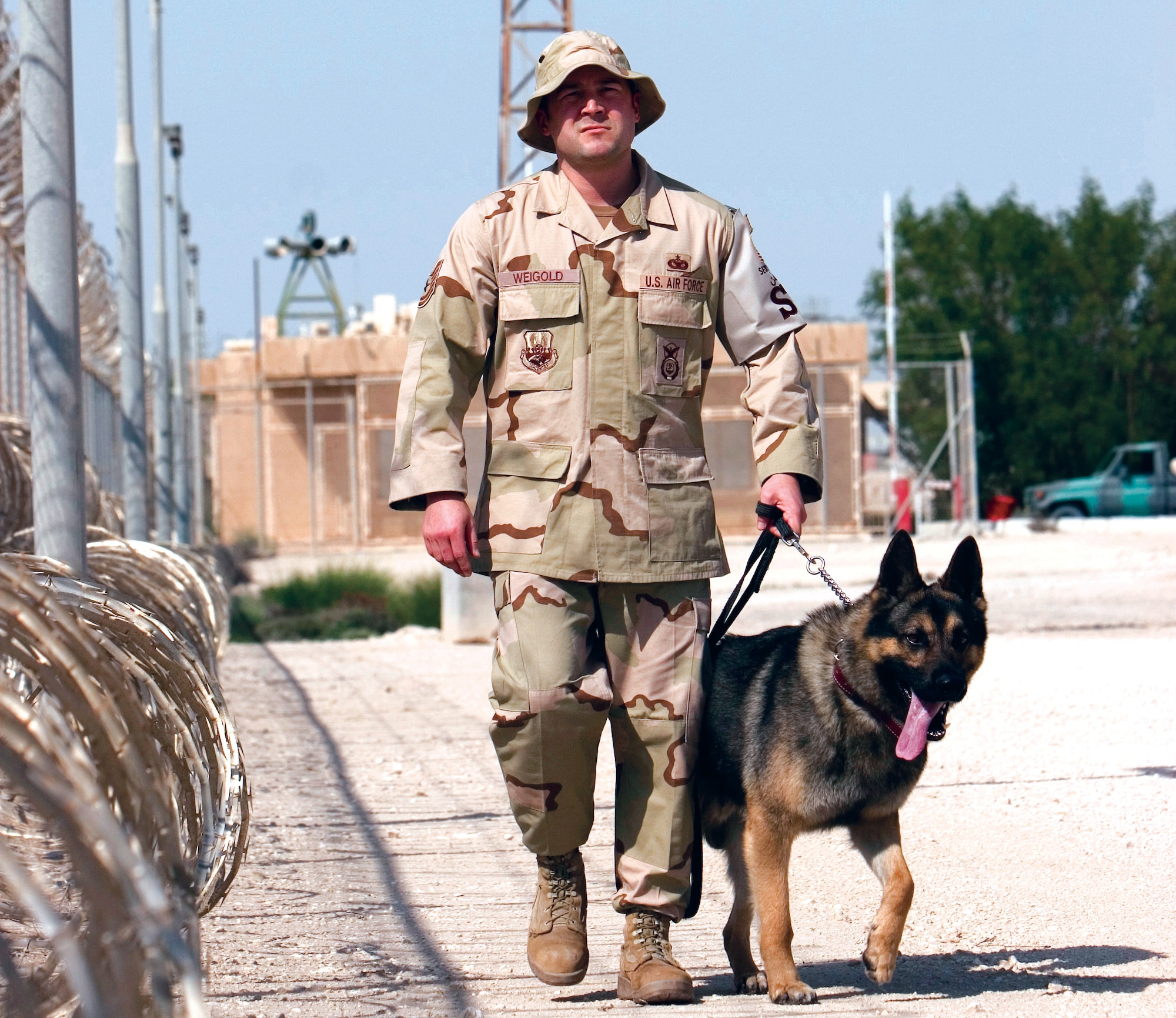 Tech. Sgt. Bob Weigold, 379th Expeditionary Security Forces Squadron Military Working Dog Section element leader, walks his explosive detection dog, Timo, along the perimeter of the base. (Photo by Tech. Sgt. Frank Hatcher)