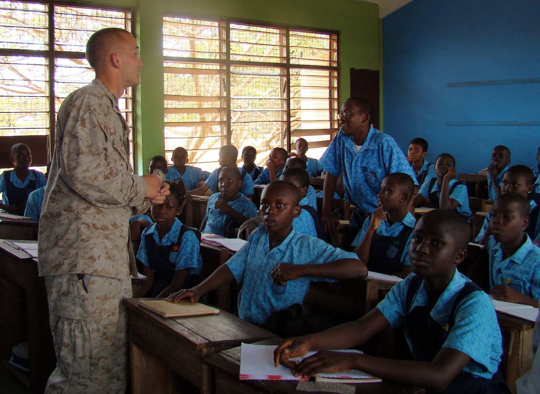 Marines stress importance of education::n::ACCRA, Ghana – Lance Corporal Grant Garab, security forces Marine with the 2nd Fleet Anti-terrorism Security Team, 6th Platoon, leans in to hear a question from a student at the Air Force Base School here Feb. 19. U.S. Marines out of Rota Naval Air Station, Spain, visited the school to answer questions from the students and stress the importance of staying in school. U.S. Armed Forces members are in Accra as part of a joint task force providing infrastructure, aircraft and personnel in support of the President's visits to Benin, Tanzania, Rwanda, Ghana and Liberia Feb. 16 to 21. (U.S. Air Force photo by Tech. Sgt. Denise Johnson)