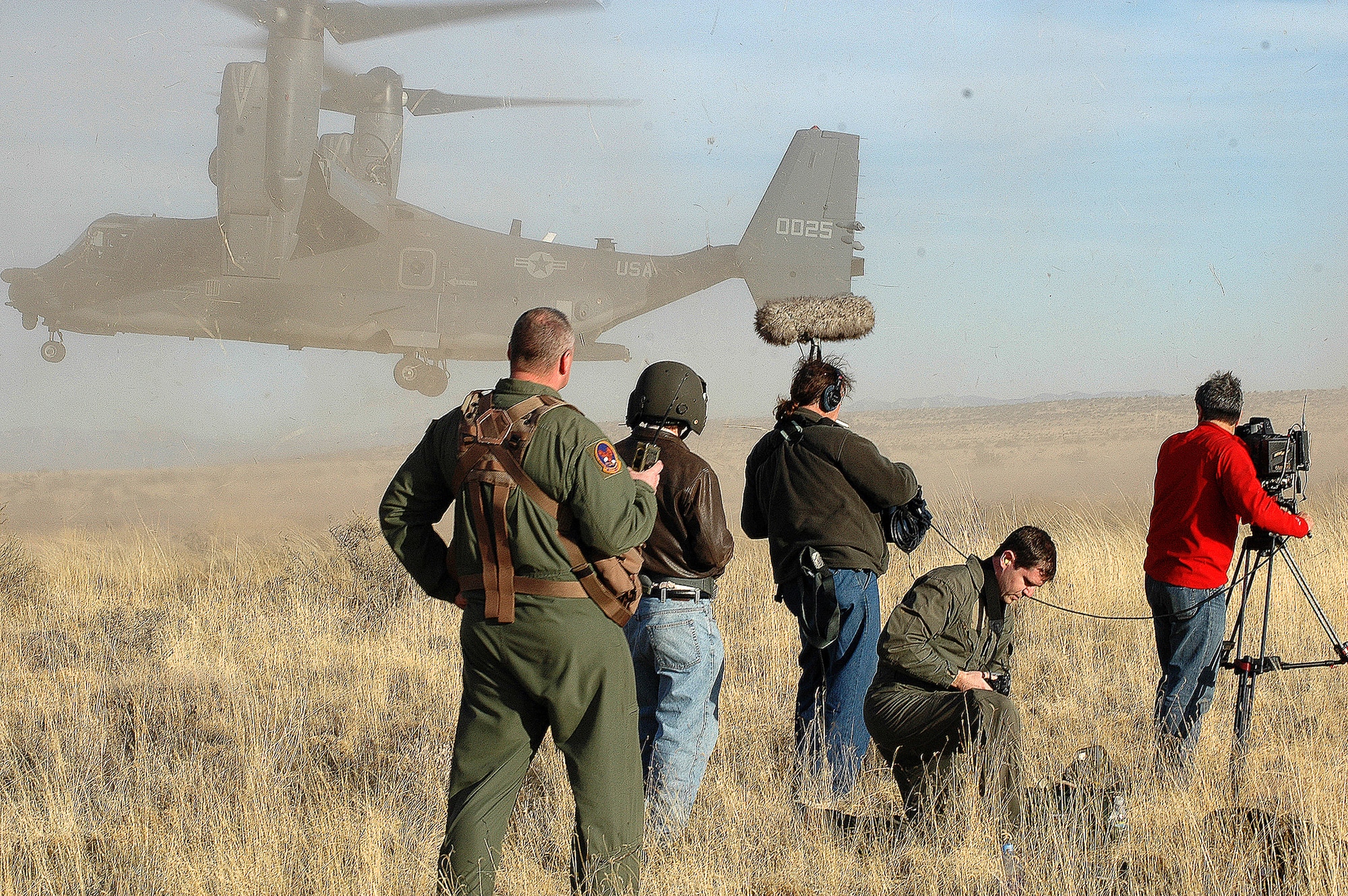 Three reporters working with the History Channel, accompanied by James Darcy (kneeling), V-22 Osprey Program public affairs officer, and a flight engineer from the 71st Special Operations Squadron, film a CV-22 Osprey during a training mission at a landing zone here for a show called Modern Marvels ? Military Movers. (U.S. Air Force photo by Staff Sgt. Markus Maier)
