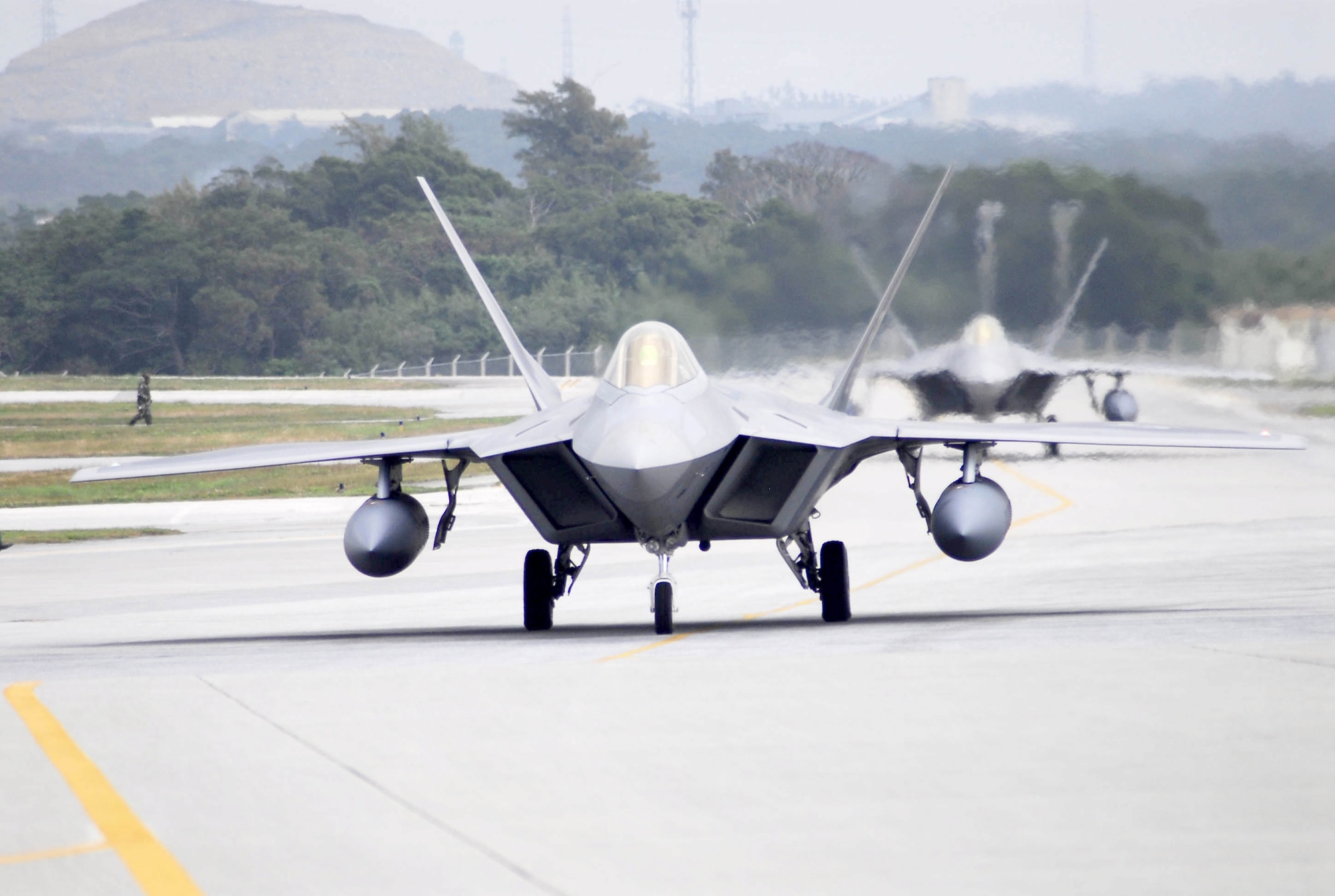 Two F-22 Raptors taxi after landing at Kadena Air Base, Japan, Feb. 18, marking the aircraft's first overseas deployment. The jets are two of 12 along with more than 250 Airmen deployed from Langley Air Force Base, Va., to Kadena as part of an air expeditionary force rotation. (U.S. Air Force photo/Airman Sheila deVera)
