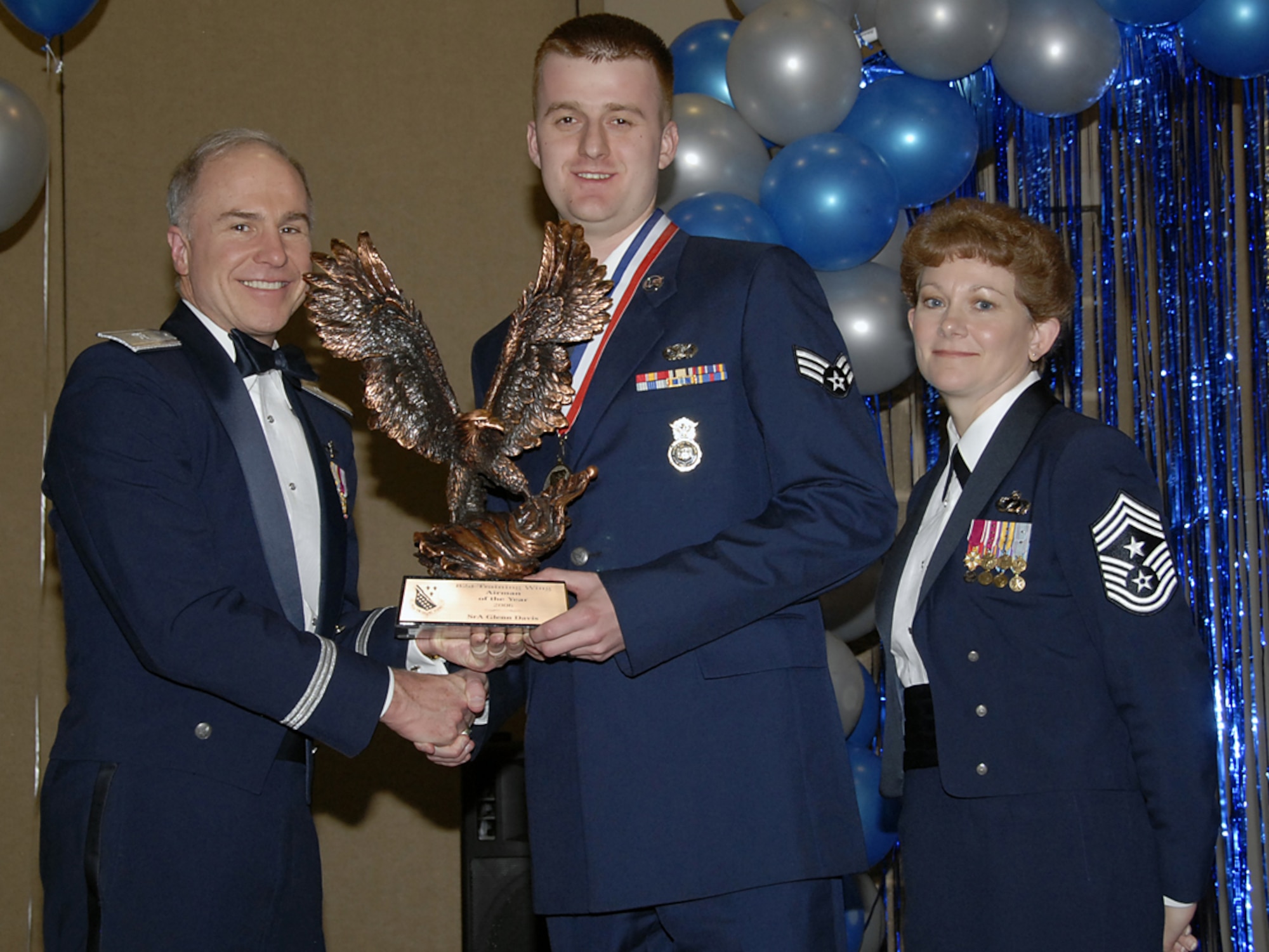 Brig. Gen. Richard Devereaux, 82nd Training Wing commander, and Command Chief Chief Master Sgt. Jeannie McLean present a trophy Feb. 16 to Senior Airman Glenn Davis, the 2006 Airman of the Year winner for the wing. Airman Davis, a member of the 82nd Security Forces Squadron, set himself apart while deployed ot Iraq. He led a fire team during 11 mortar and rocket strikes, as well as securing the scene at two improvised explosive device incidents. (U.S. Air Force photo/Sandy Wassenmiller)