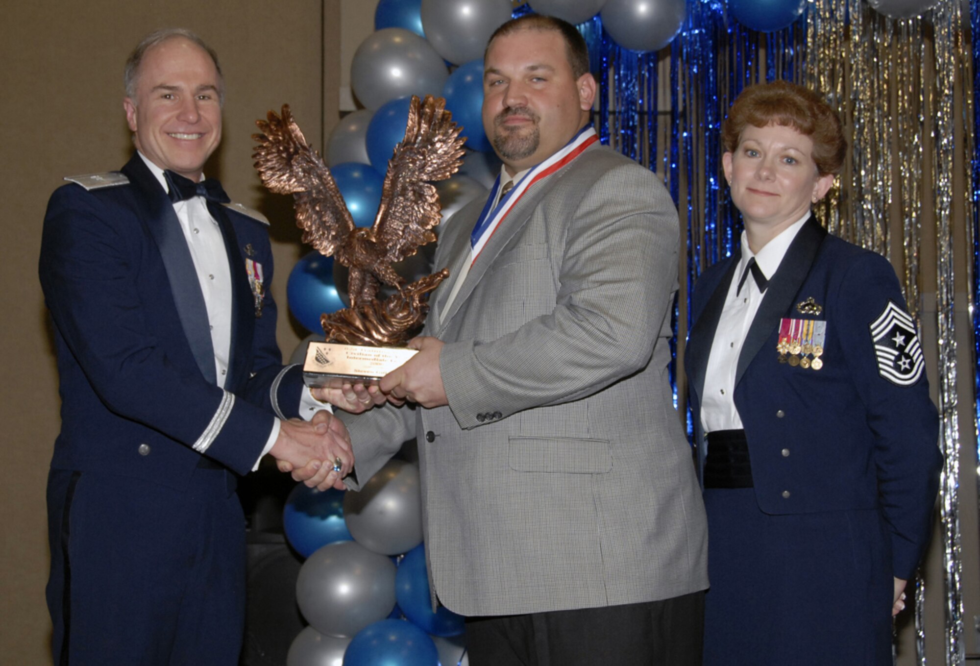Steven Gifford, center,  of the 364th Training Squadron receives his award Feb. 16 as the 2006 Intermediate-level Civilian of the Year. Mr. Gifford efforts during September's Operational Readiness Inspection helped the squadron and the 82nd Training Wing earn an Excellent rating. He wrote the first ever mobile tower climbing and climbing certification courses for the cable and antenna career field. Also pictured with Mr. Gifford are 82nd TRW Commander Brig. Gen. Richard Devereaux and Chief Master Sgt. Jeannie McLean, the 82nd TRW command chief. (U.S. Air Force photo/Sandy Wassenmiller)