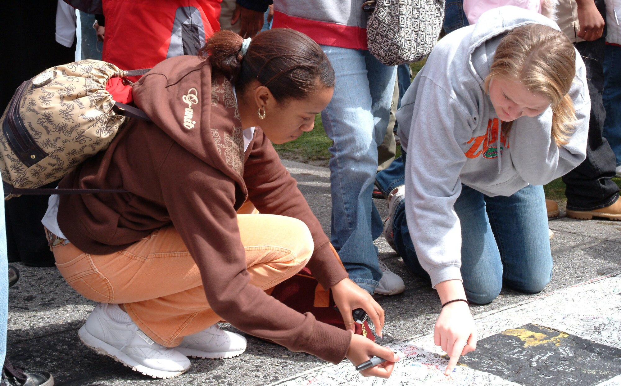 Newly enlisted Airmen Sabrina Robinson (left) and Krystal Brant sign on another "dotted line," the start-finish line of Daytona, NASCAR's most famous track, during their infield tour before the Daytona 500 race.  Earlier in the day, 36 delayed-entry-program recruits were enlisted into the Air Force by Gen. Ronald Keys, Air Combat Command commander.  (U.S. Air Force photo/Staff Sgt. Samuel King Jr.)
