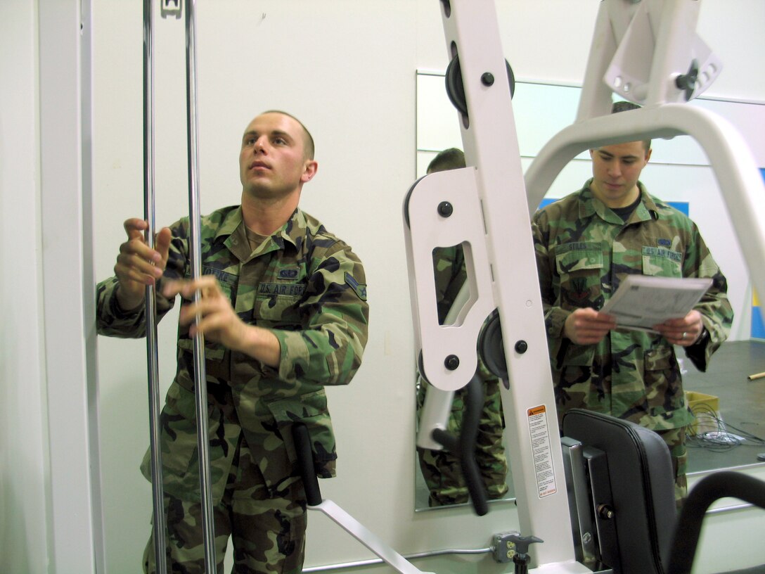Twenty eighth Services Squadron fitness specialists Airman 1st Class Patrick Totzke (left) and Senior Airman Charles Stiles work together to assemble the latest addition to the Ellsworth Bellamy Fitness Center’s family room. The universal machine being assembled is the sixth piece of equipment to join the ensemble of treadmills, elliptical trainers and stationary bike available to parents who choose to take advantage of the recently renovated area that helps military members maintain combat readiness while keeping children supervised.  The room reopened Feb. 6. (U.S. Air Force photo/Staff Sgt. Shanda L. De Anda)