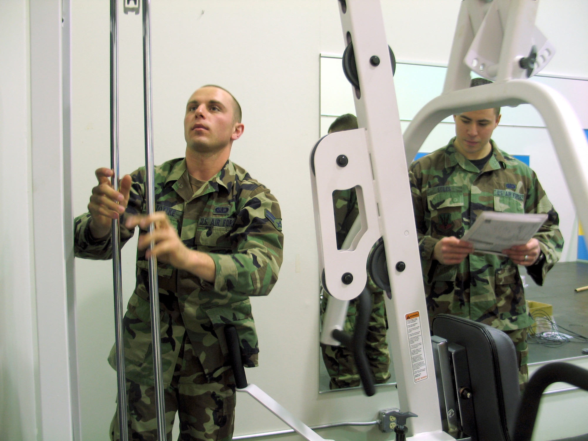 Twenty eighth Services Squadron fitness specialists Airman 1st Class Patrick Totzke (left) and Senior Airman Charles Stiles work together to assemble the latest addition to the Ellsworth Bellamy Fitness Center’s family room. The universal machine being assembled is the sixth piece of equipment to join the ensemble of treadmills, elliptical trainers and stationary bike available to parents who choose to take advantage of the recently renovated area that helps military members maintain combat readiness while keeping children supervised.  The room reopened Feb. 6. (U.S. Air Force photo/Staff Sgt. Shanda L. De Anda)