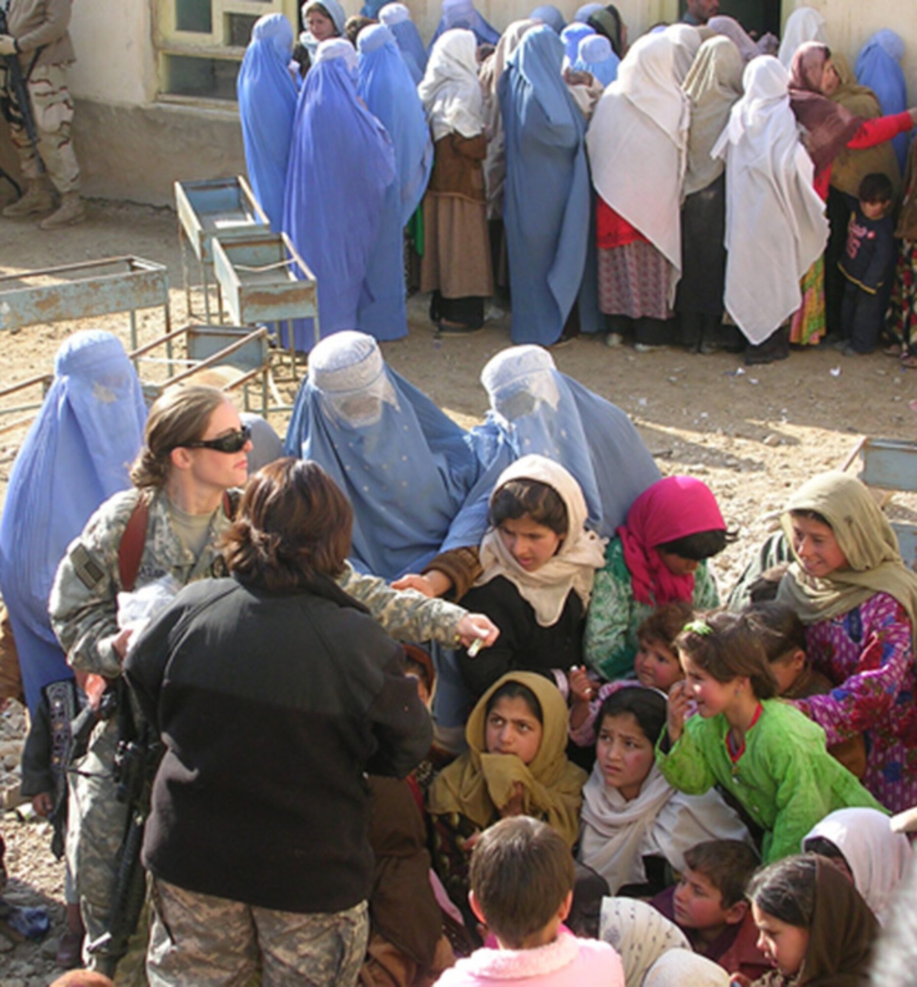 PANJSHIR PROVINCE, Afghanistan -- Air Force Senior Airman Melissa Laclair and interpreter Shahla Hammond, both from the Panjshir Provincial Reconstruction Team, distribute lip balm to women and children outside a Medical Civic Action Program event Feb. 17. Nearly 300 women and children and 150 men were seen and treated in the Shutol District by medical personnel from the Panjshir PRT and the Cooperative Medical Assistance team from Combined Joint Task Force 76.  (Courtesy photo by Army Reserve Maj. Cliff White).
