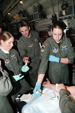 Senior Airmen Bethany Walsh (left) and Rachel Husser, 934th Aeromedical Evacuation Squadron  prepare an IV during a training mission as Instuctor Master Sgt. Chris Reese looks on.  AES members trained while deploying to Luke AFB, Ariz. where they conducted joint training with the 944th Aeromedical Staging Squadron and also supported the 944th Fighter Wing Employer's Day. (Air Force Photo/Master Sgt. Paul Zadach)