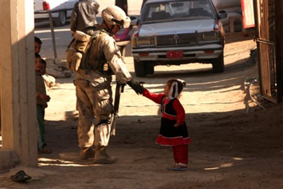 U.S. Marine Corps Staff Sgt. Chris Conner, platoon sergeant assigned to the 3rd Platoon, Golf Company, Battalion Landing Team 2/4, interacts with a local child while conducting clearing operations in Barwanah, Iraq. The California-based Marines conducted a sweep and clear operation through the city. 