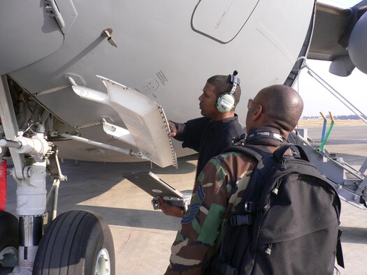 YOKOTA AIR BASE, Japan -- Staff Sgt. Kirk Jackson, 730th Air Mobility Squadron, inspects the nose landing gear door on a C-17 Globemaster cargo aircraft while being observed by Senior Master Sgt. Darryle White, and inspector from Travis Air Force Base. (U.S. Air Force photo by Master Sgt. Scott Samdahl)