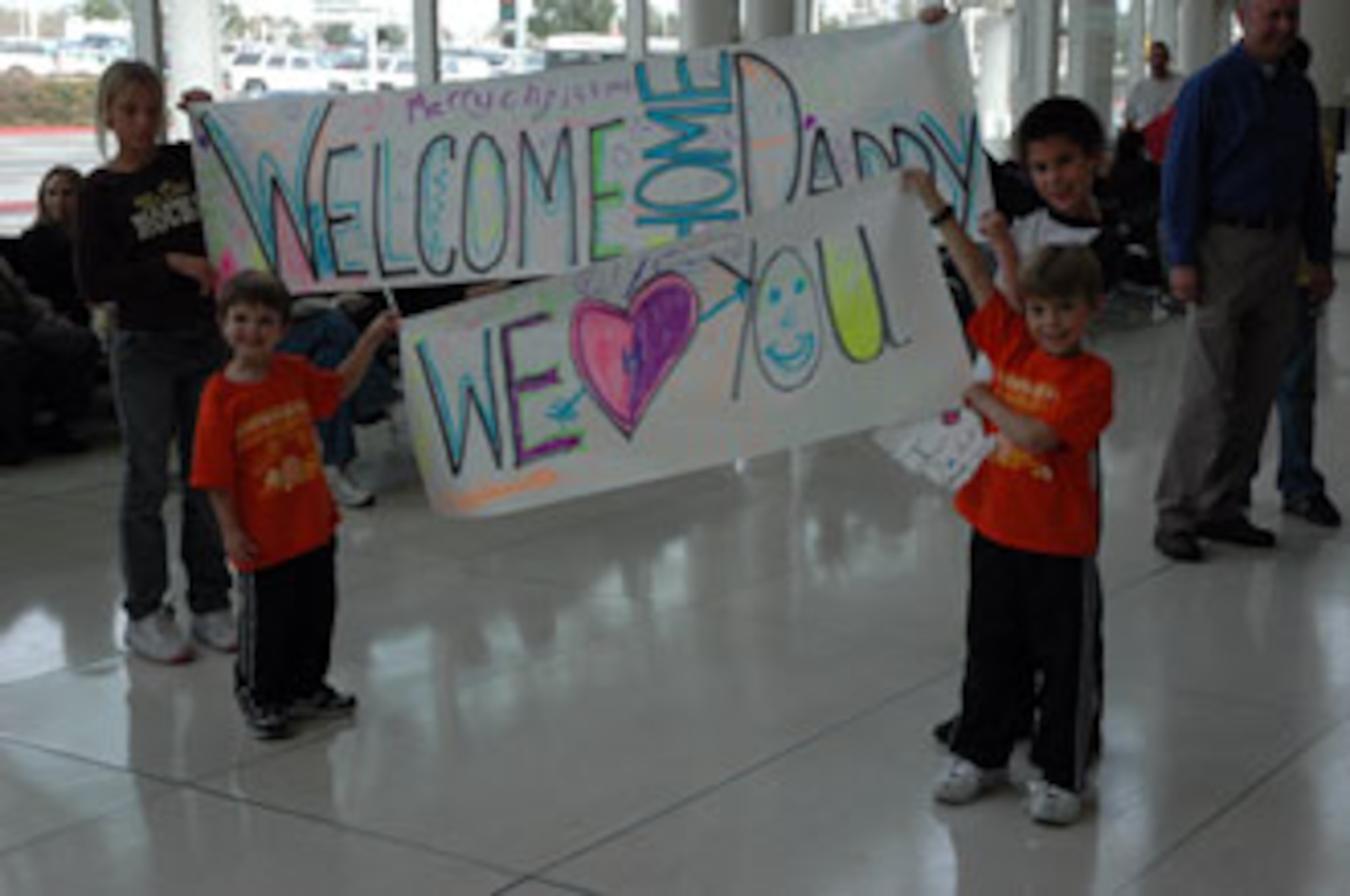 Anxious family members hold banners in anticipation of their father's arrival.  The children were waiting at Ontario Airport with other 163rd RW members and families. (U.S. Air Force photo by Maj. Brenda Hendricksen)