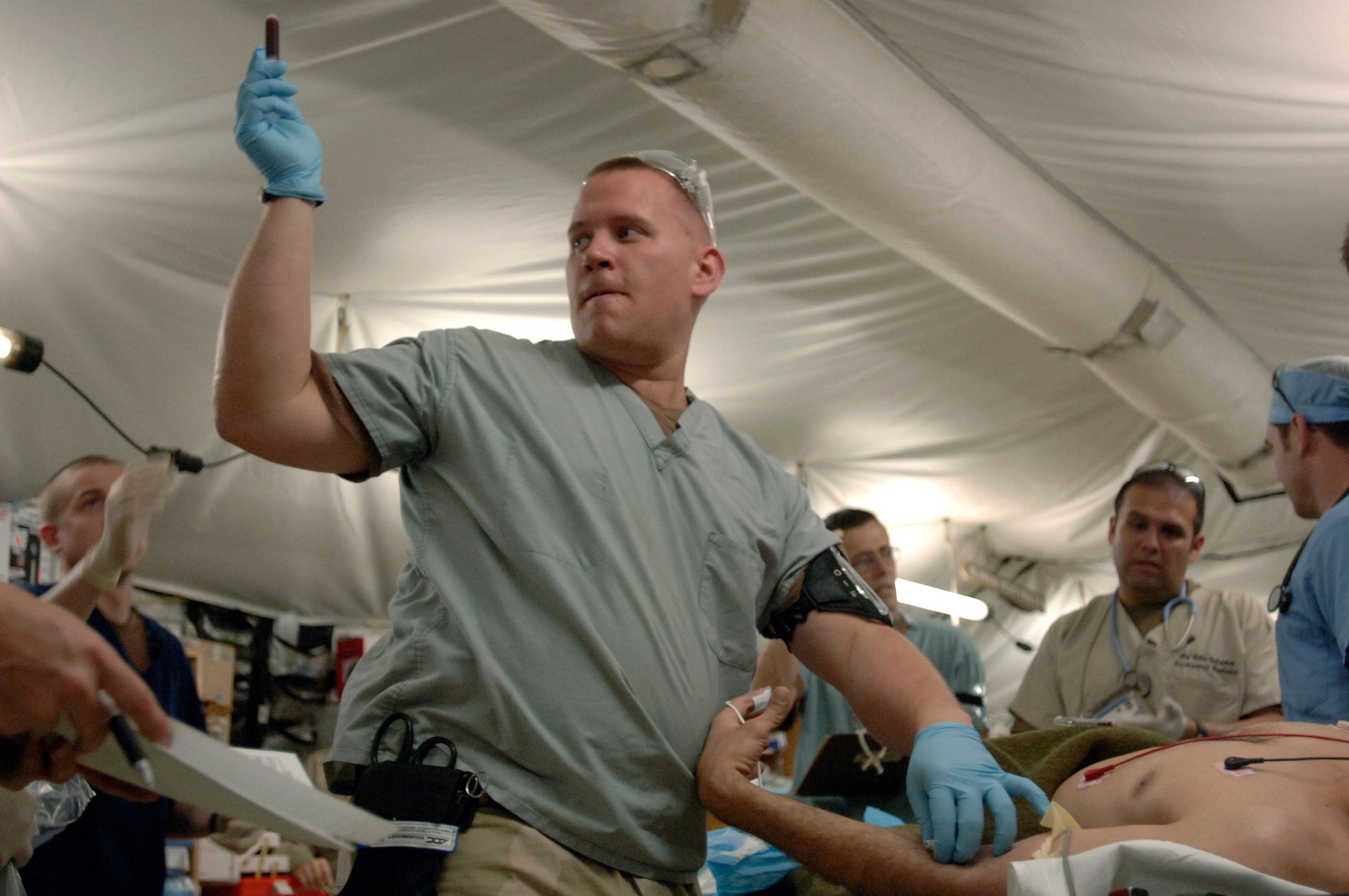 Staff Sgt. Donovan O'Linc passes a liter of drawn blood to a nurse at the Air Force Theater Hospital. Sergeant O'Linc is an aerospace medical technician assigned to the 332nd Expeditionary Medical Group at Balad Air Base, Iraq. Sergeant O'Linc's days are filled with this type of rapid treatment at Balad's medical facility.  (U.S. Air Force photo/Tech. Sgt. Cecilio M. Ricardo Jr.)