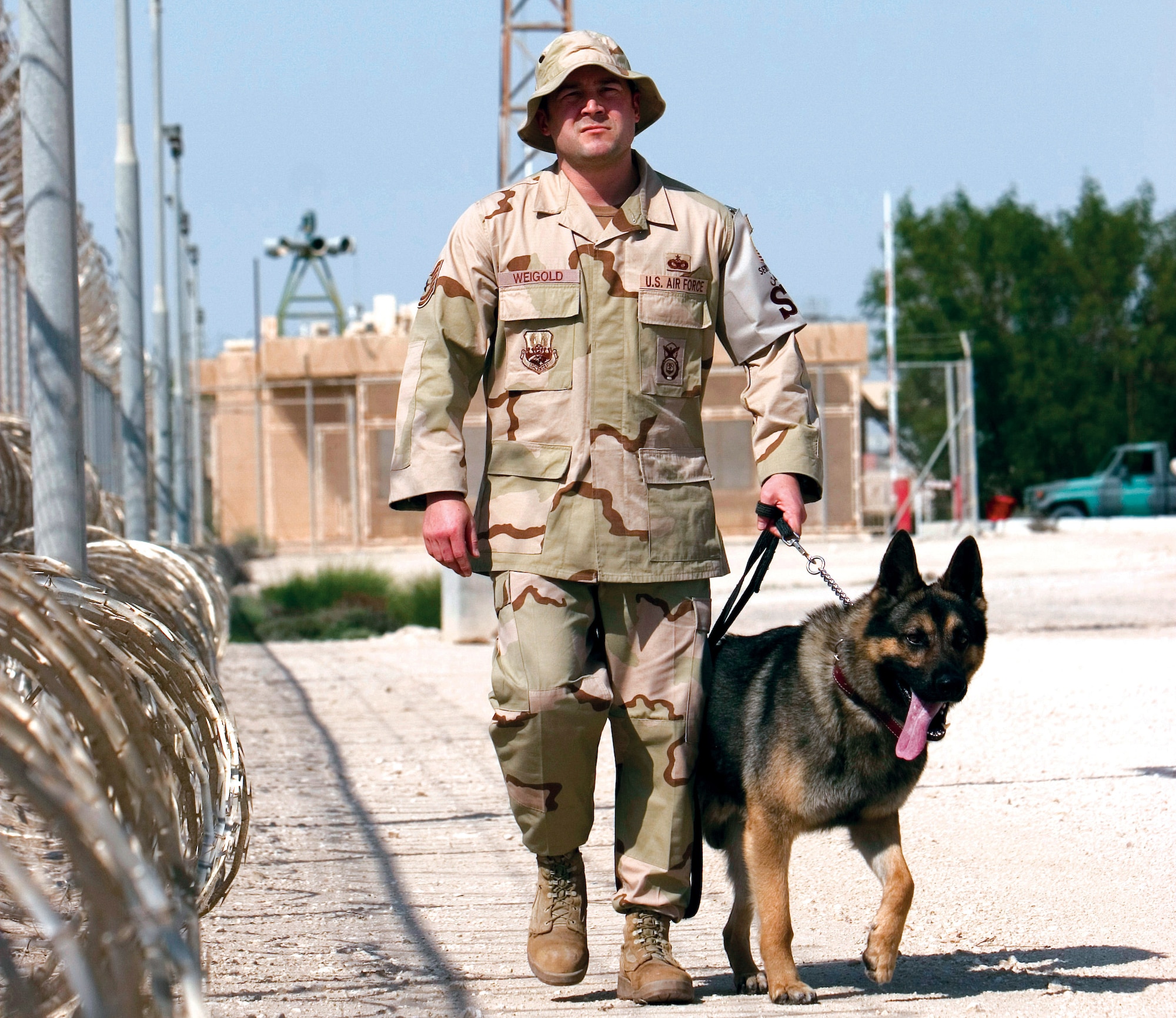 Tech. Sgt. Bob Weigold walks his explosive detection dog, Timo, along the perimeter of the base Feb. 13 in Southwest Asia. Sergeant Weigold is the 379th Expeditionary Security Forces Squadron Military Working Dog Section element leader. (U.S. Air Force photo/Tech. Sgt. Frank Hatcher)