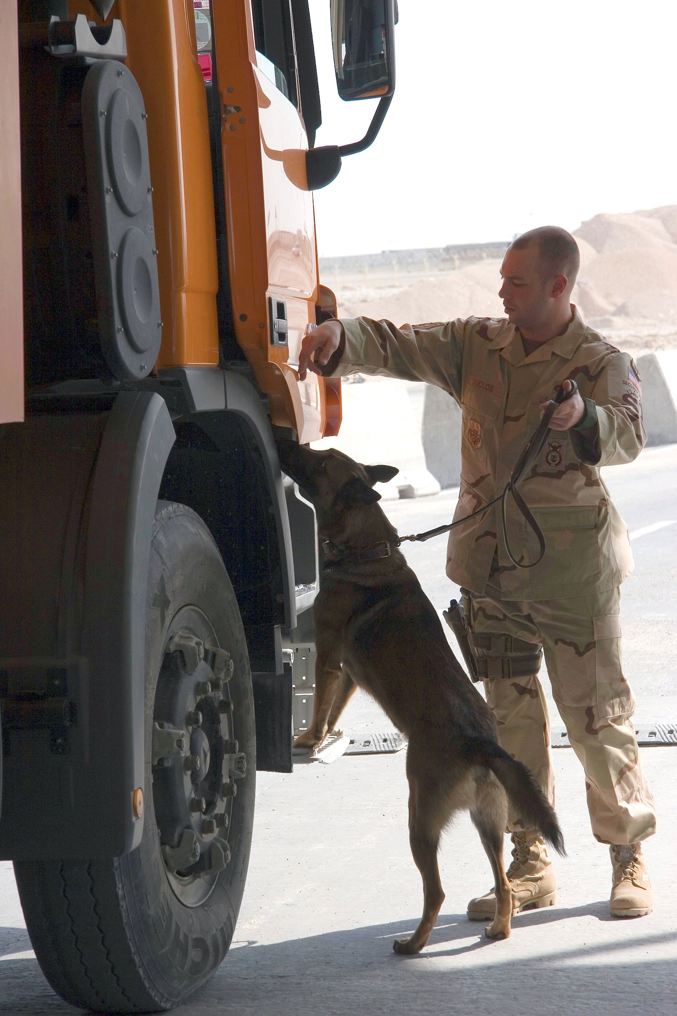 Staff Sgt. Spencer Duclos conducts a vehicle search with his dog, Boo, at the vehicle search pit Feb. 13 in Southwest Asia. Sergeant Duclos is a military working dog handler assigned to the 379th Expeditionary Security Forces Squadron. (U.S. Air Force photo/Tech. Sgt. Frank Hatcher) 
