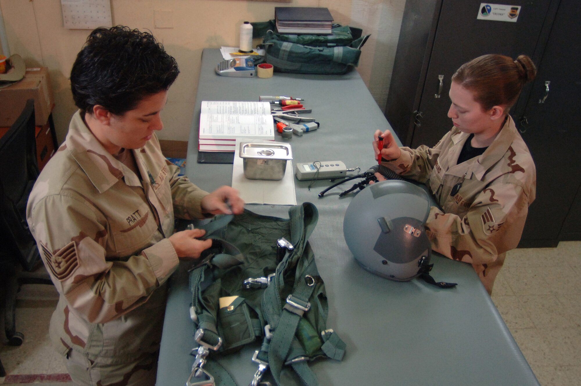 Tech. Sgt. Jill Pratt and Senior Airman Daniel Gerrard, 510th Expeditionary Fighter Squadron life support technicians,  inspect a flight harness and flight helmet. Pilot life support equipment has to be inspected every 30 days.  Sergeant Pratt and Airman Gerrard are deployed from Aviano Air Base, Italy. 
 (Photo by Staff Sgt. Michael Holzworth)
