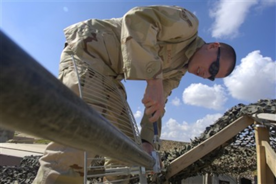 Airman 1st Class Sven Bickham, U.S. Air Force, installs a new antenna and satellite dish for cable television at Balad Air Base, Iraq, on Feb. 17, 2007.  Bickham is attached to the 332nd Expeditionary Communication Squadron.  
